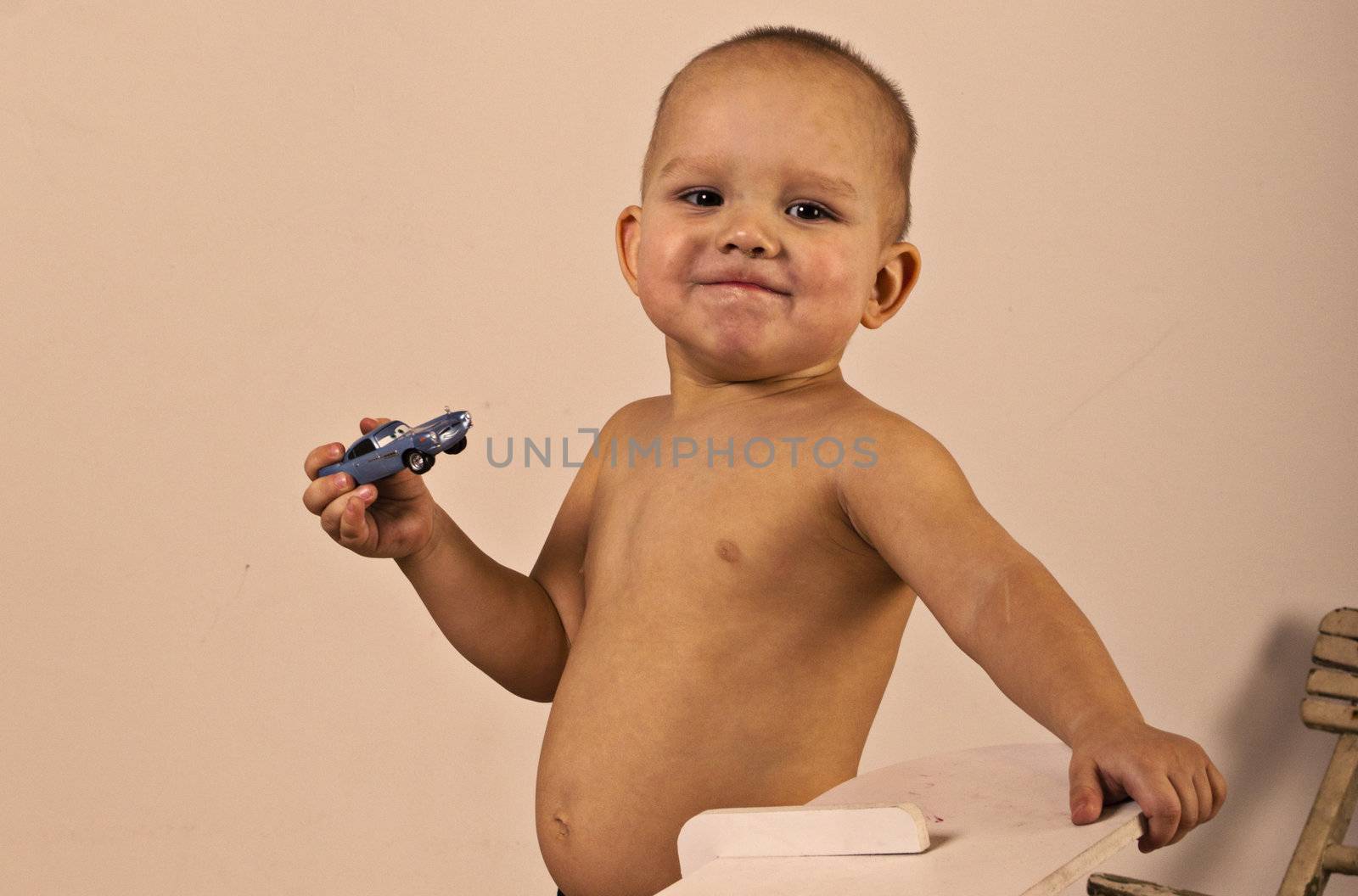 little bou is holding a toy car in his hand, and he is very proud of that.