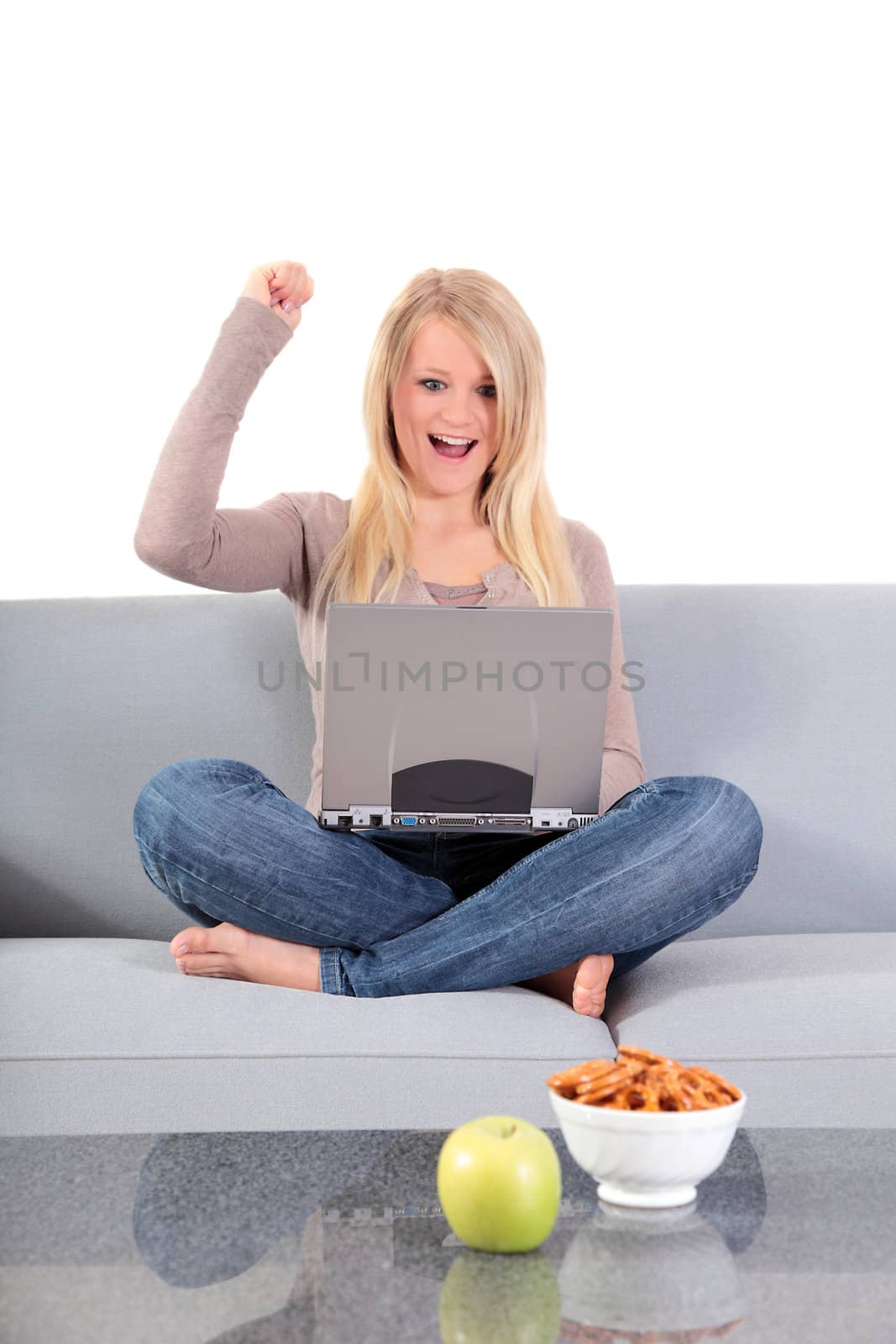 An attractive young woman cheering while surfing the internet at home.