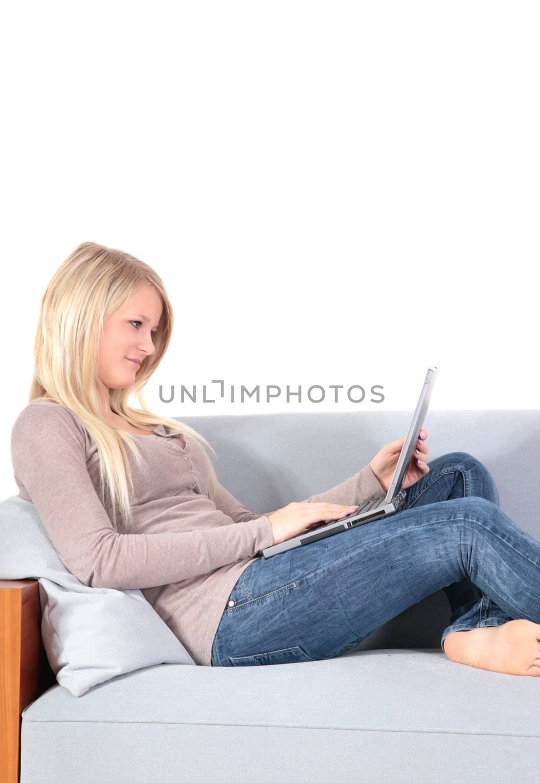 An attractive young woman using her notebook computer while sitting on a couch.