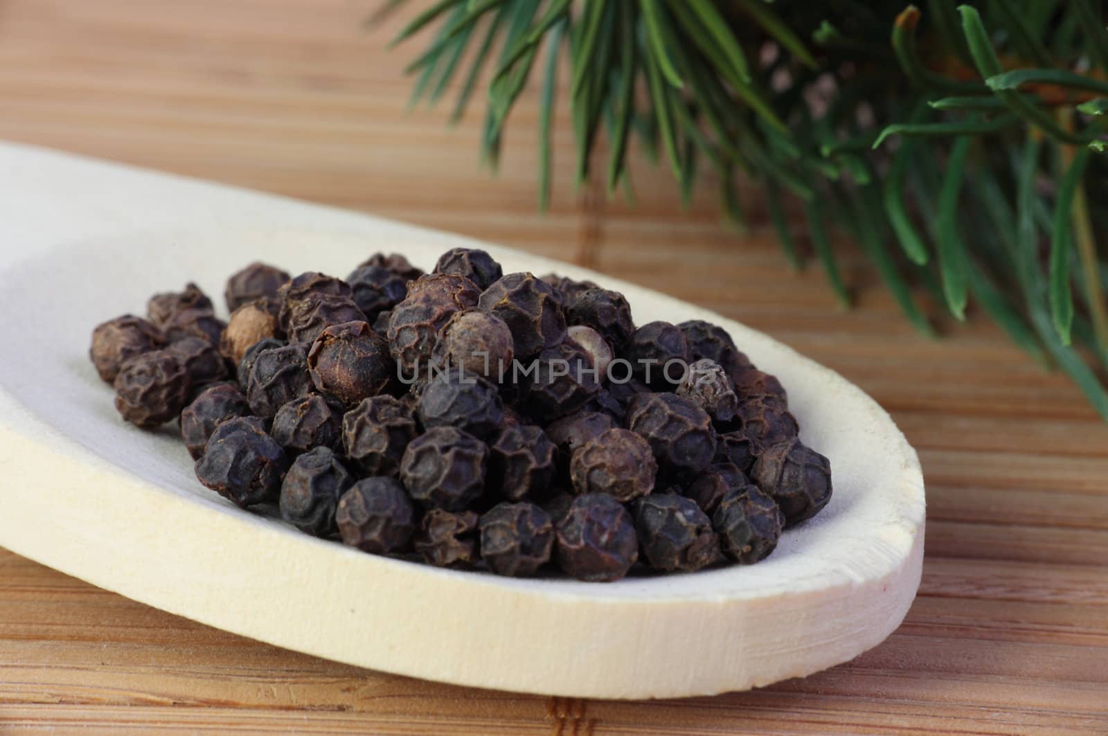 A pile of black peppercorns lying on a cooking spoon.