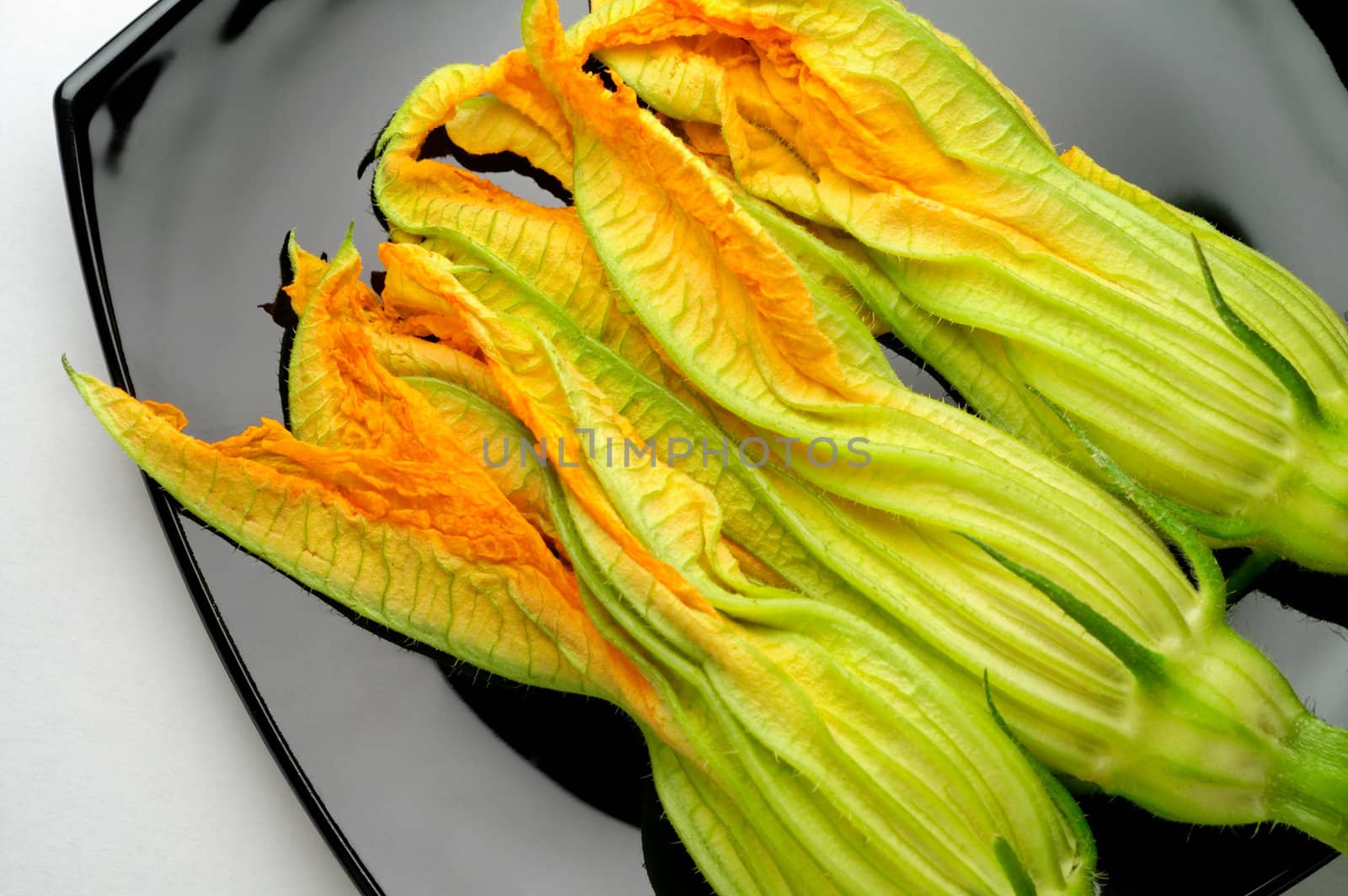 Zucchini flowers on black plate by Laborer