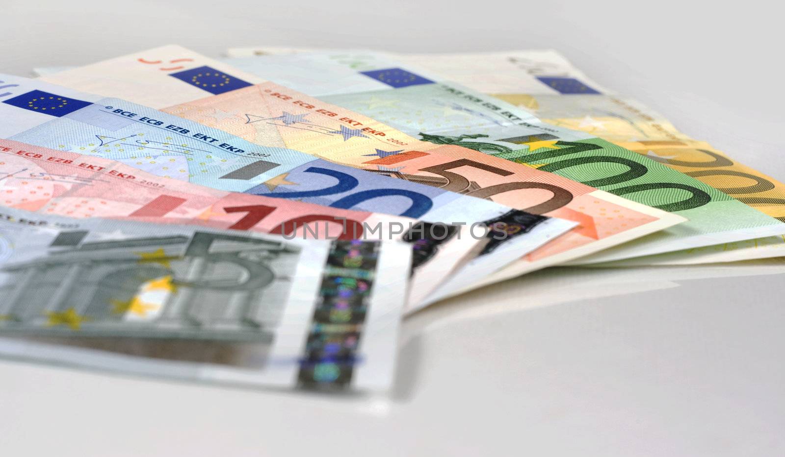 Simple shot of Euro banknotes of 200, 100, 50, 20, 10 Euros spread on a white table.

Studio shot.