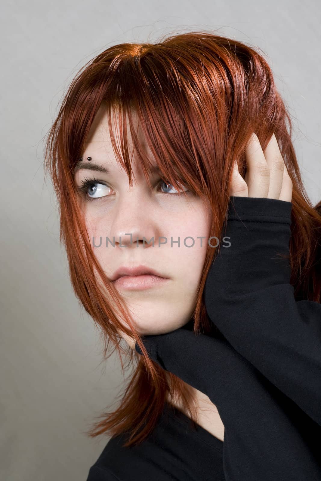 Cute redhead girl looking away. With messy hair.

Studio shot.