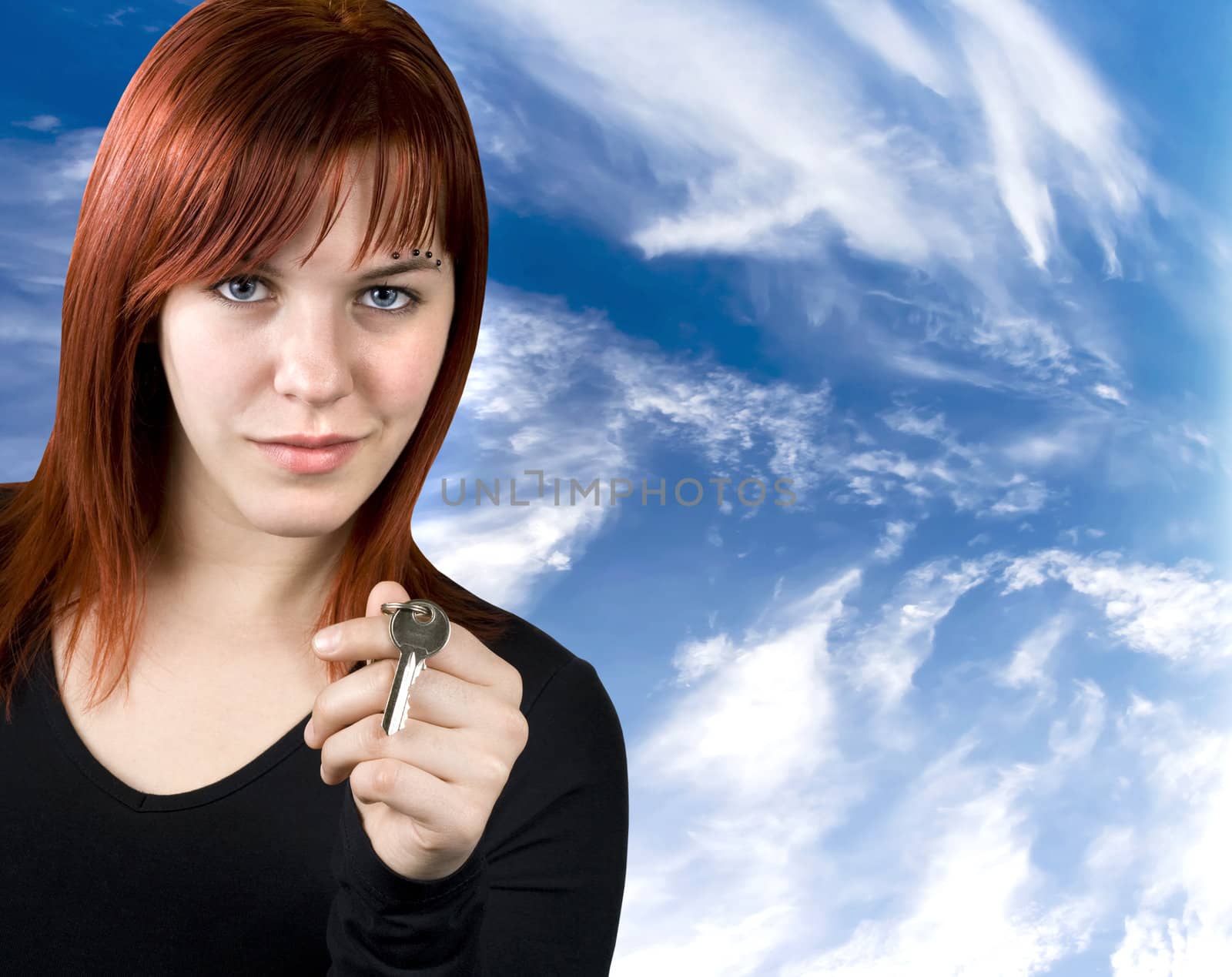Cute redhead girl holding a key in her hands. Studio shot.