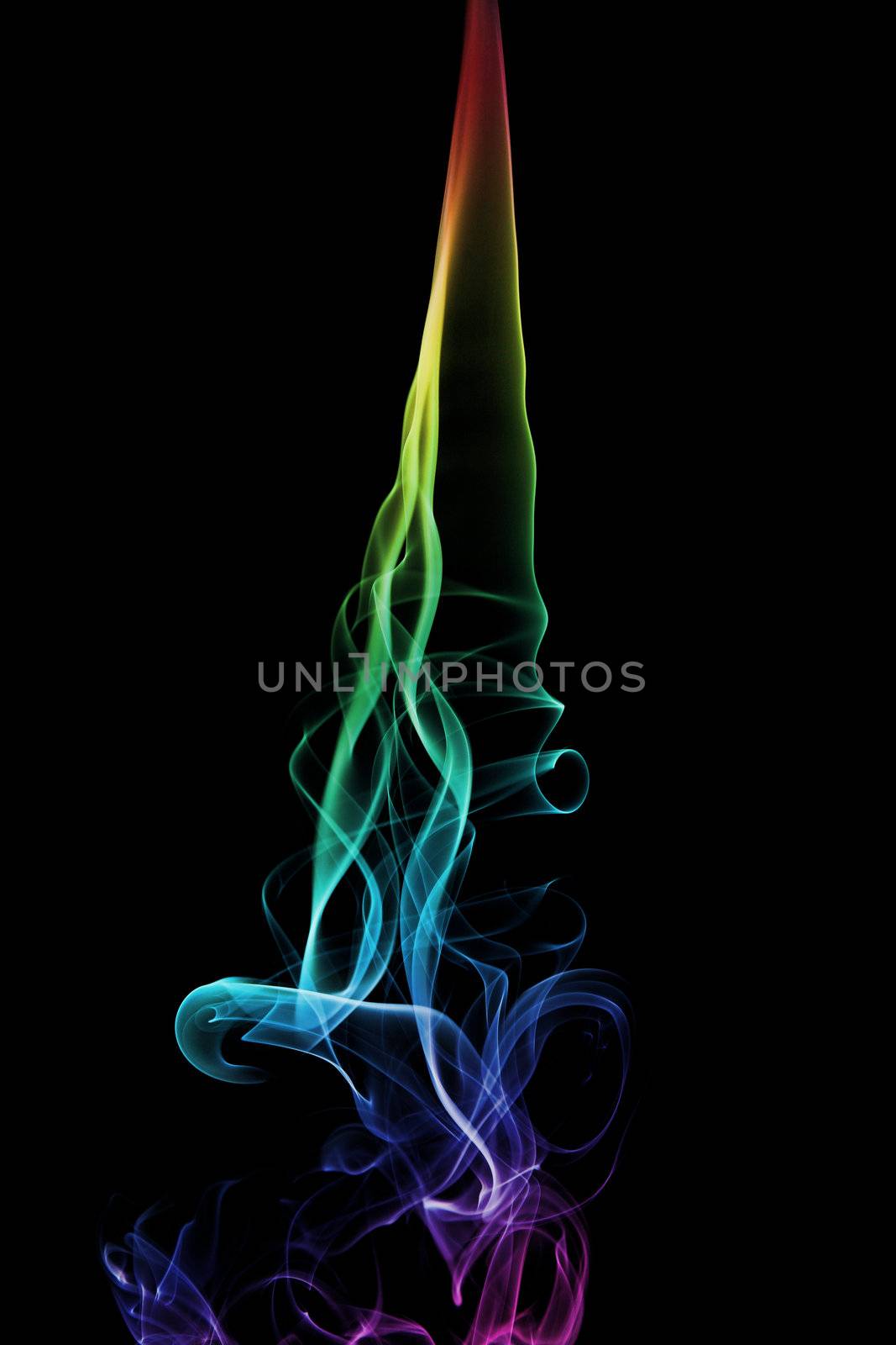 A rainbow colored smoke trail from an incense stick. Black background.