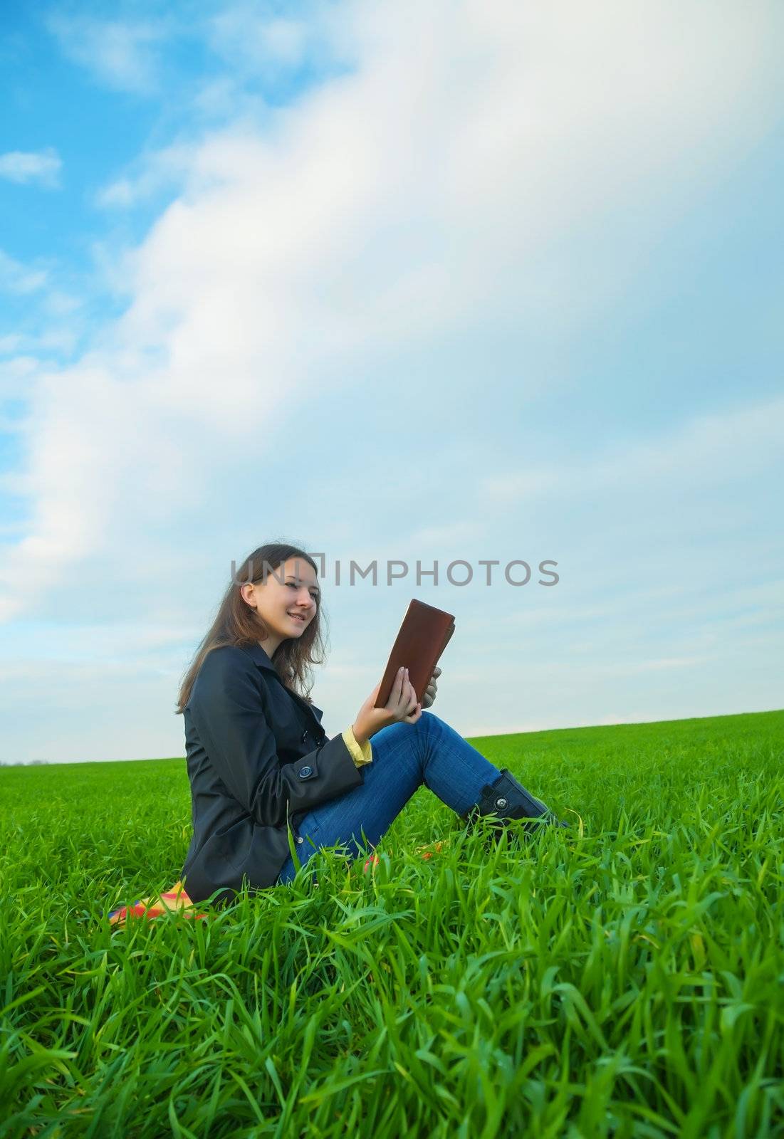Teen girl reading the Bible sitting outdoors at sunset time