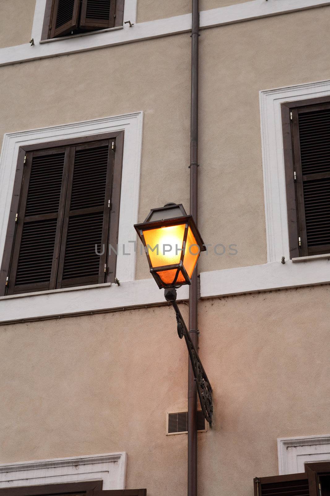 Vintage glowing street lamp hanging on the wall of building