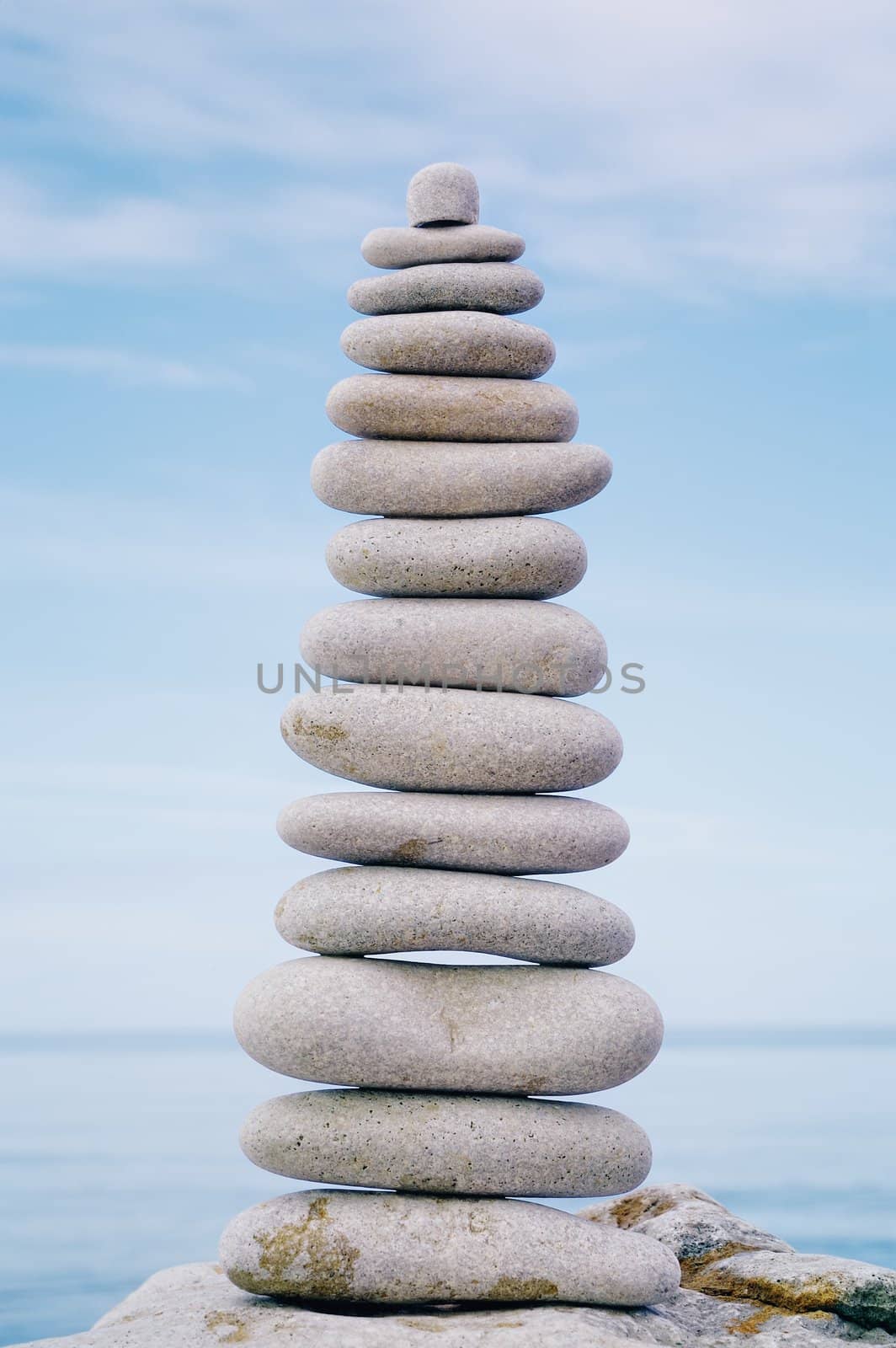 Balancing white pebbles each other on a sky background