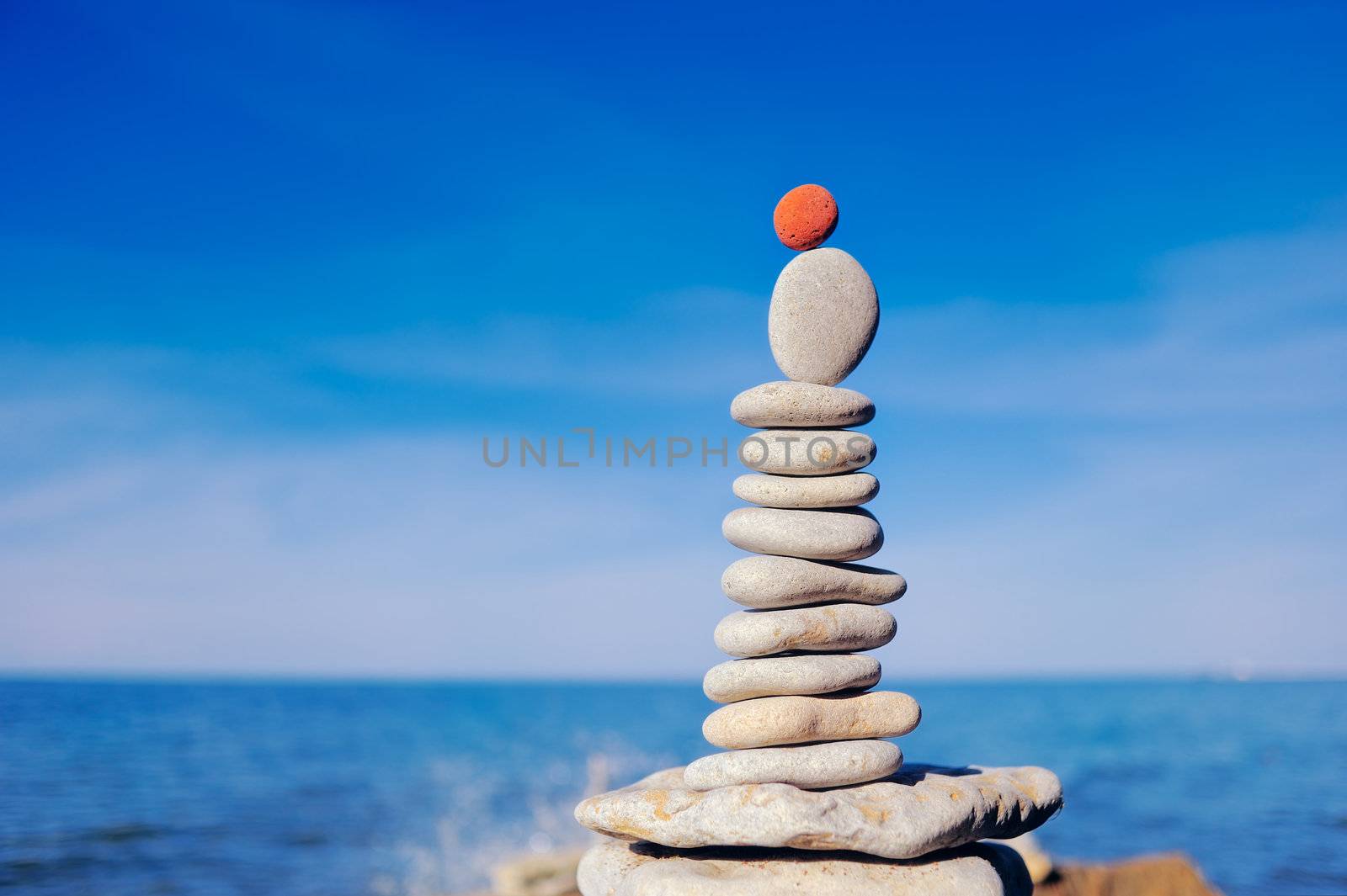 Balancing red stone on the top of pile of pebbles