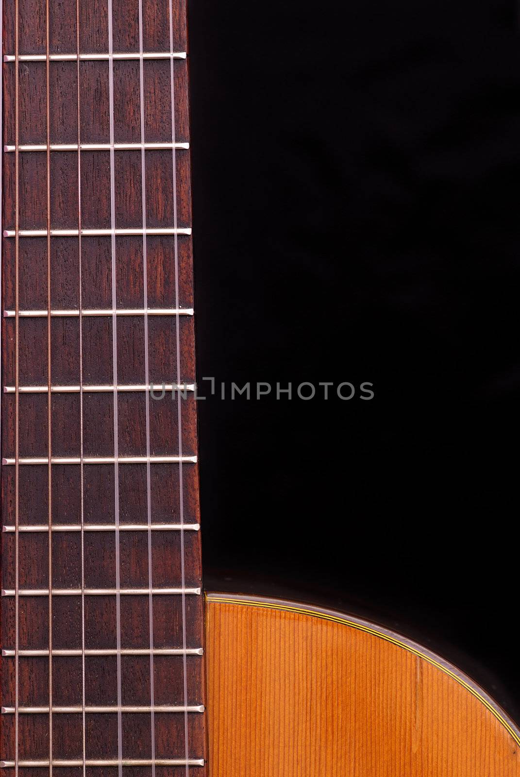 Detail of classic guitar fretboard (Spanish), against black background.