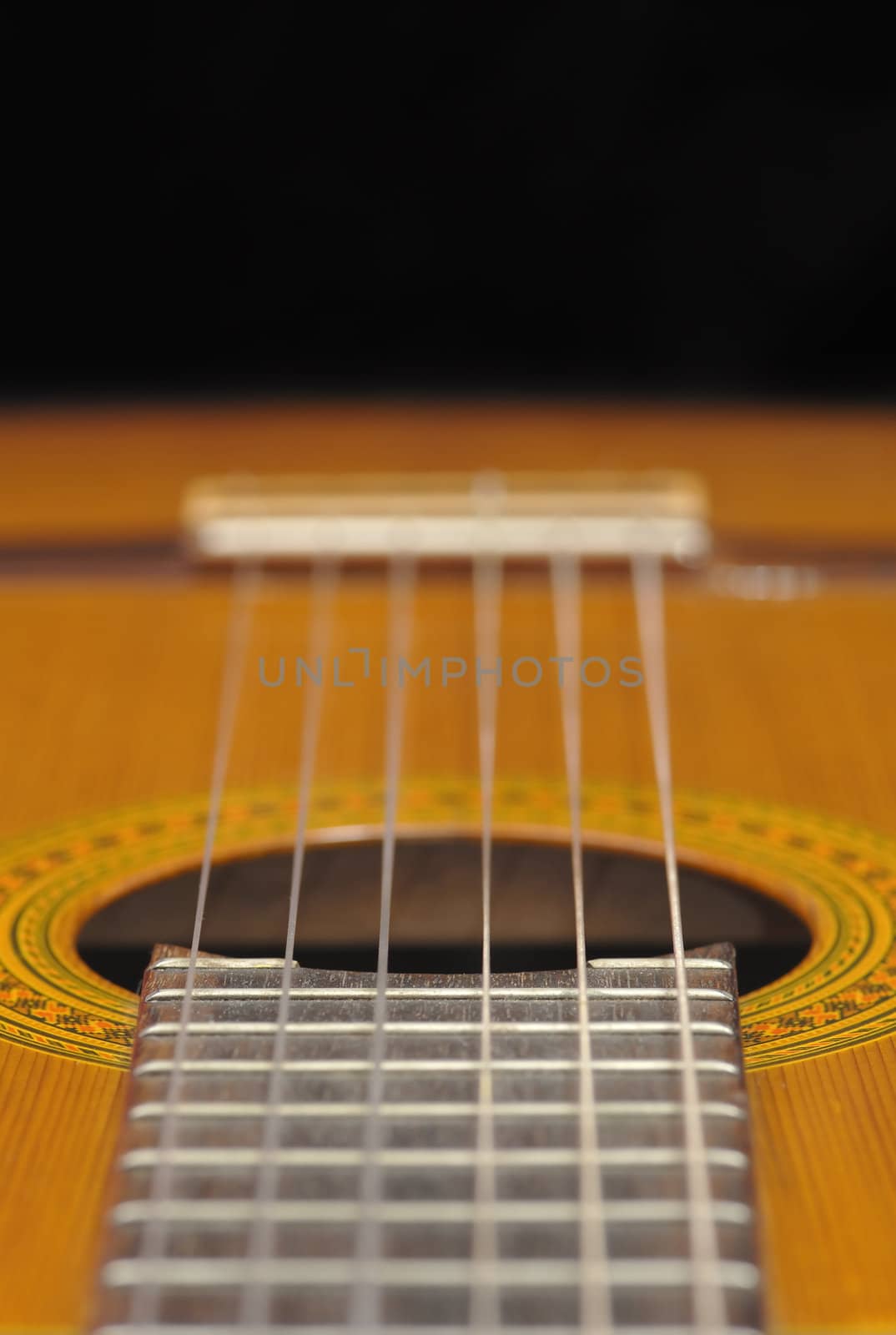 Detail of classic guitar (Spanish), against black background.