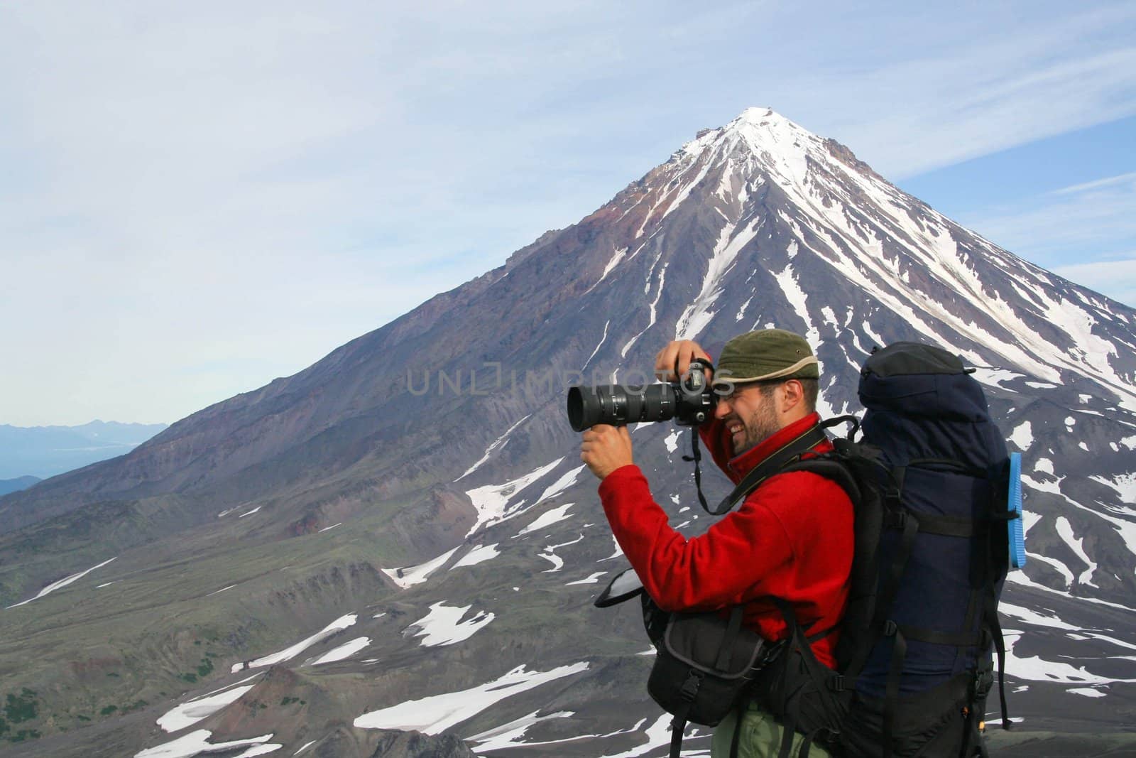 Kamchatka.Turist-photographer on the background of Koryaksky volcano.
