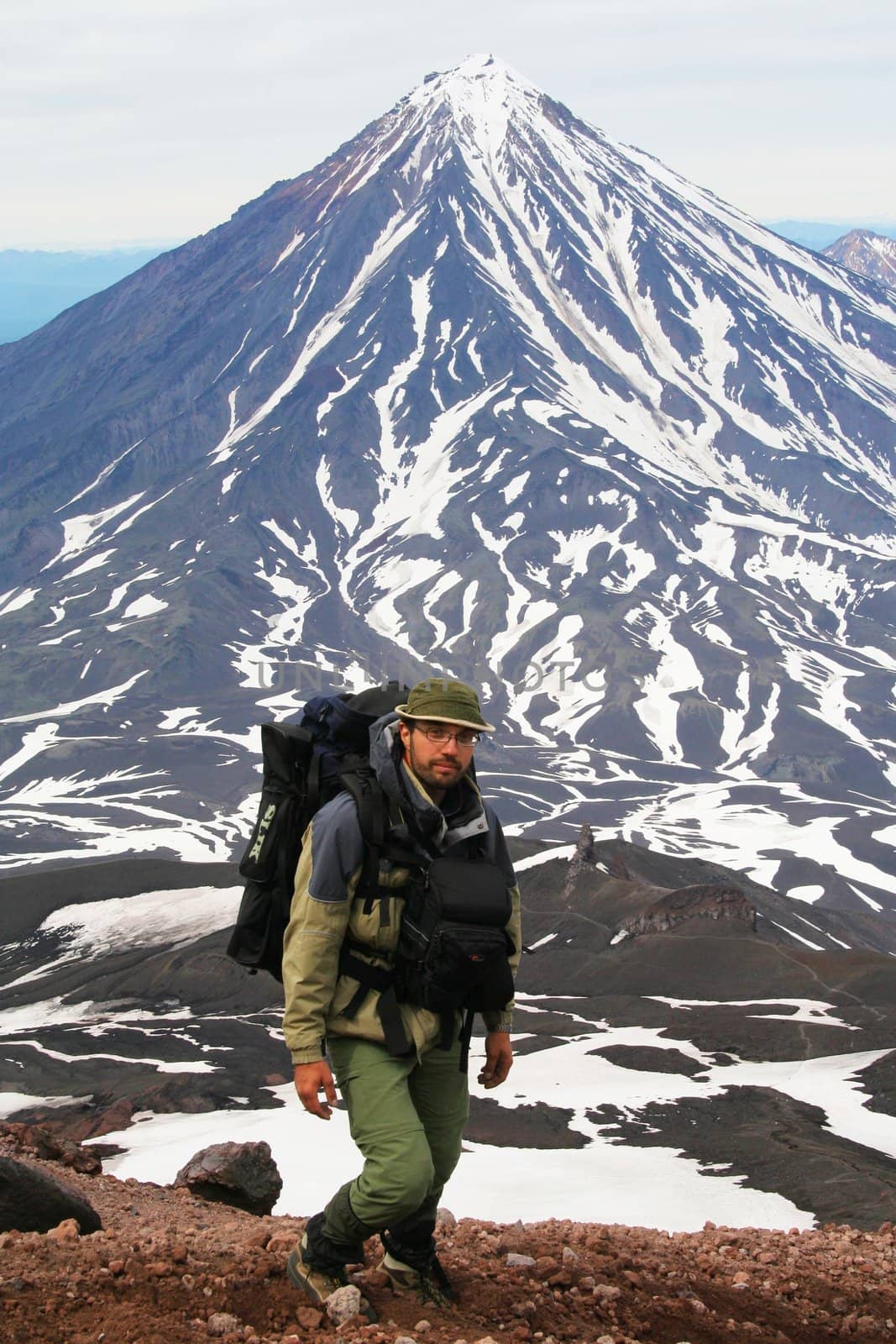 The Tourist on background  vulcano Koryakskiy. Kamchatka