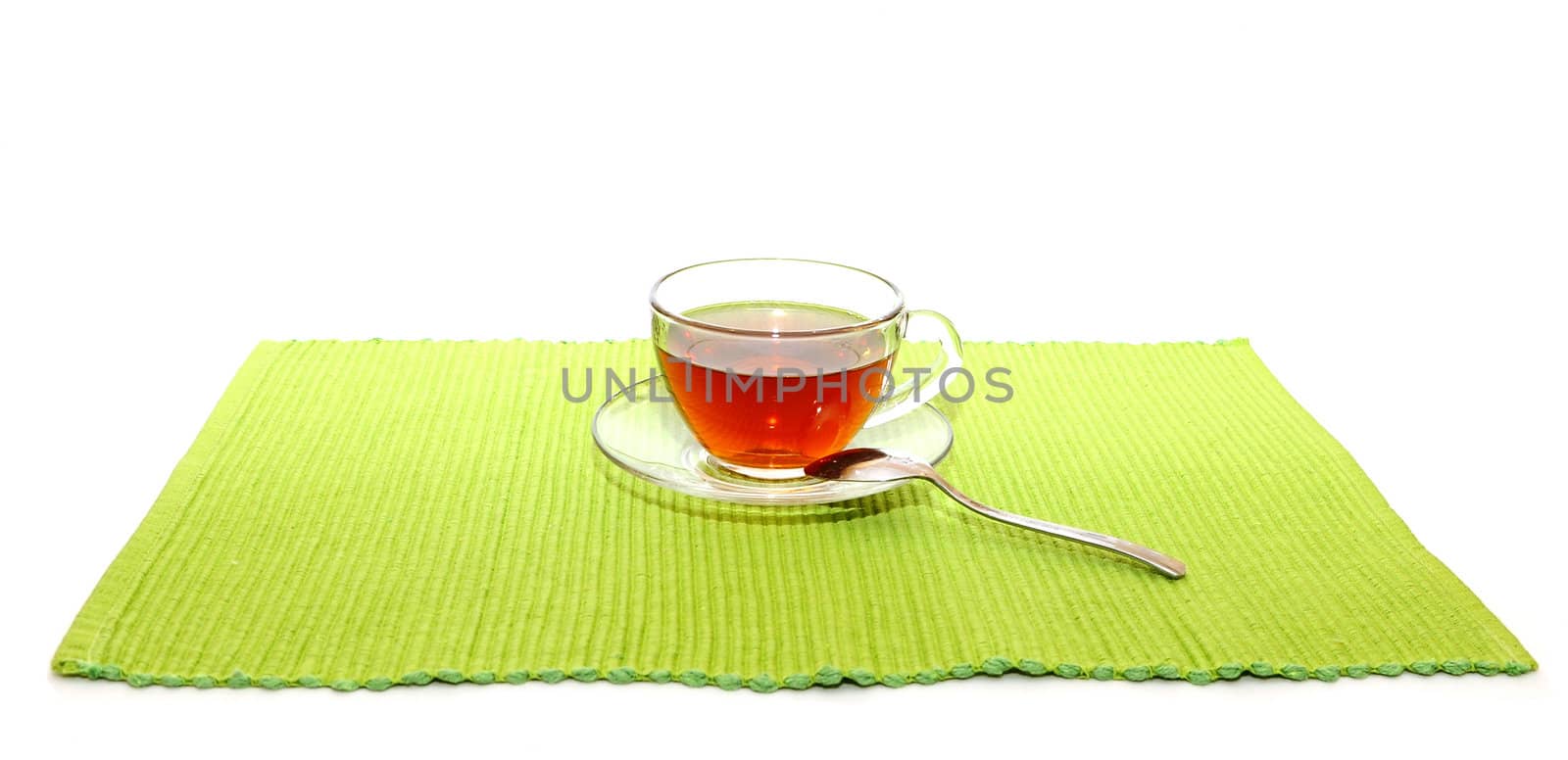 the cup of tea with spoon on the green napkin