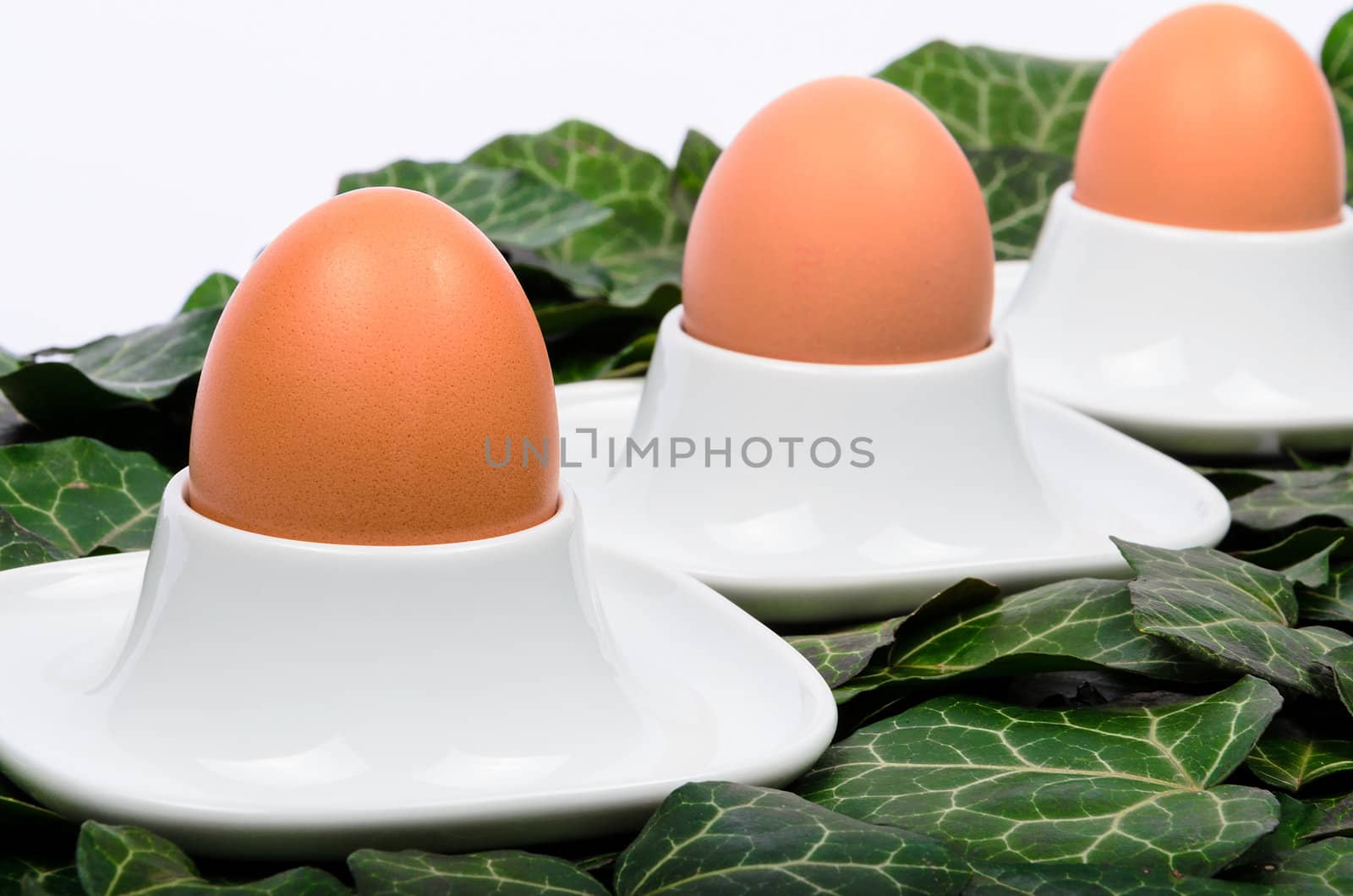 A series of three eggs and egg cups on a green background by velislava