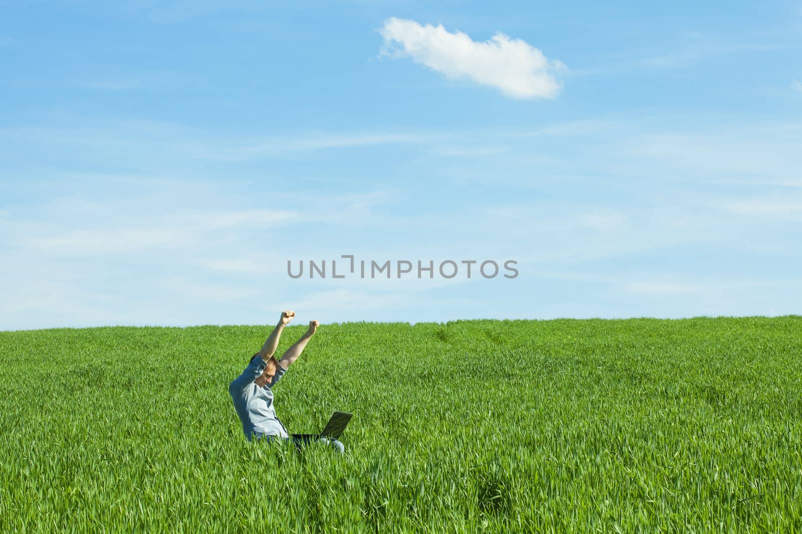 young man uses a laptop in the green field