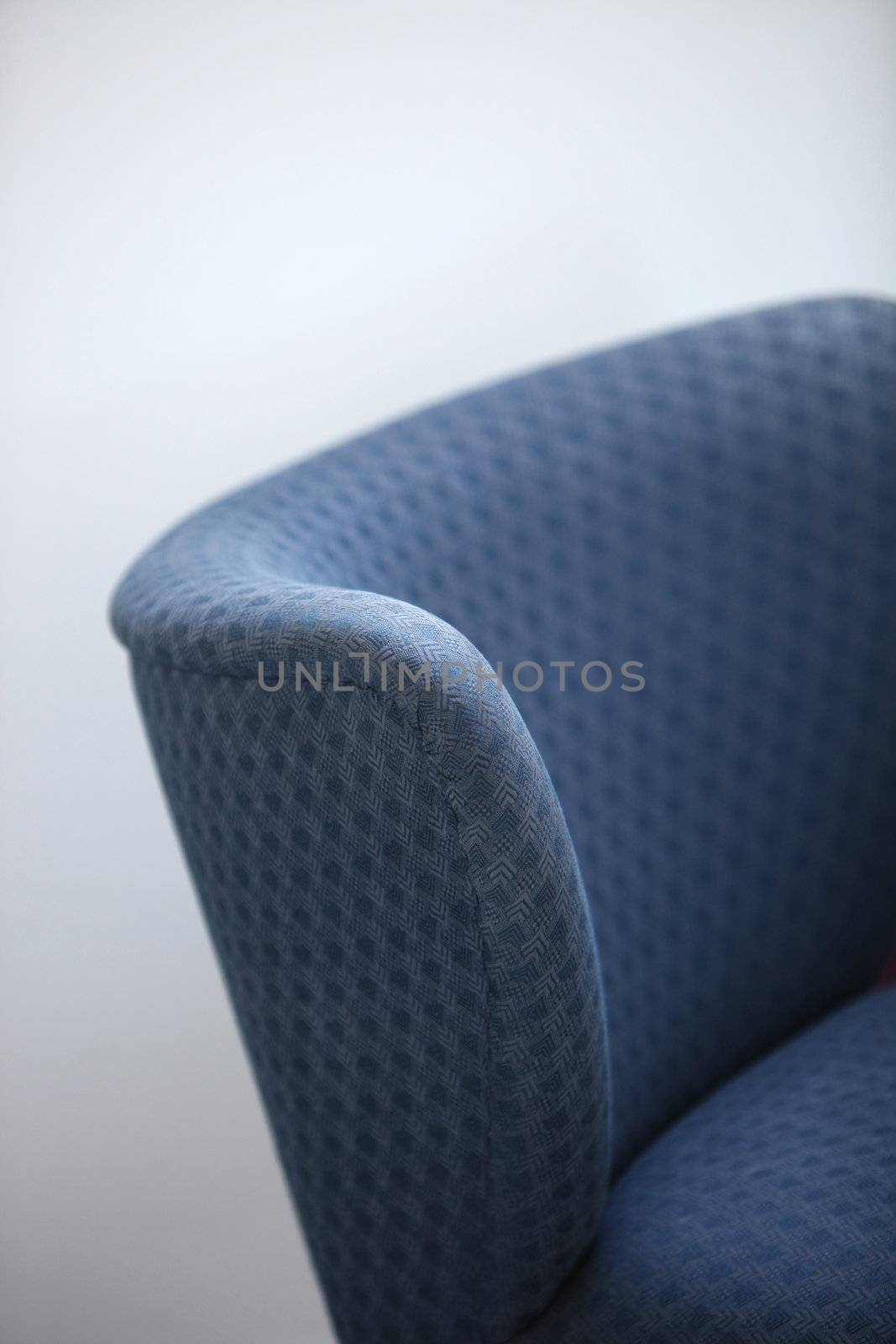 Partial view of the curved back of a comfortable retro upholstered blue chair