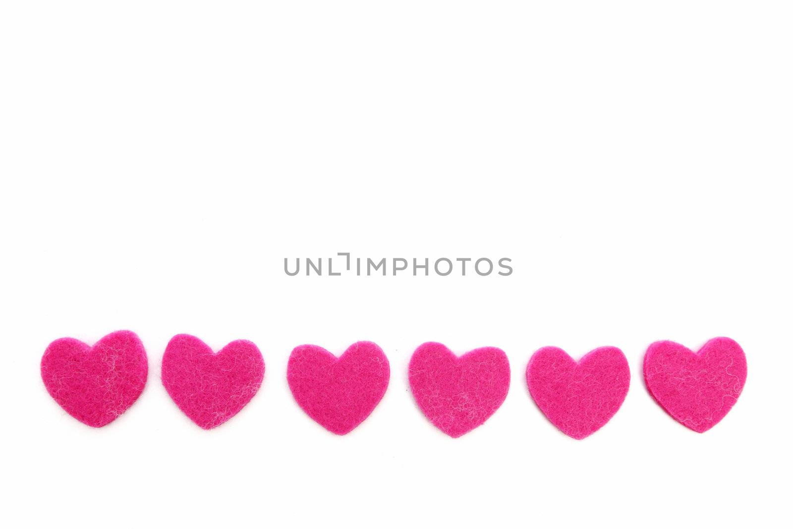 Row of romantic pink hearts made of a textile with a soft fibre texture isolated on white with copyspace for your Valentine or anniversary greeting