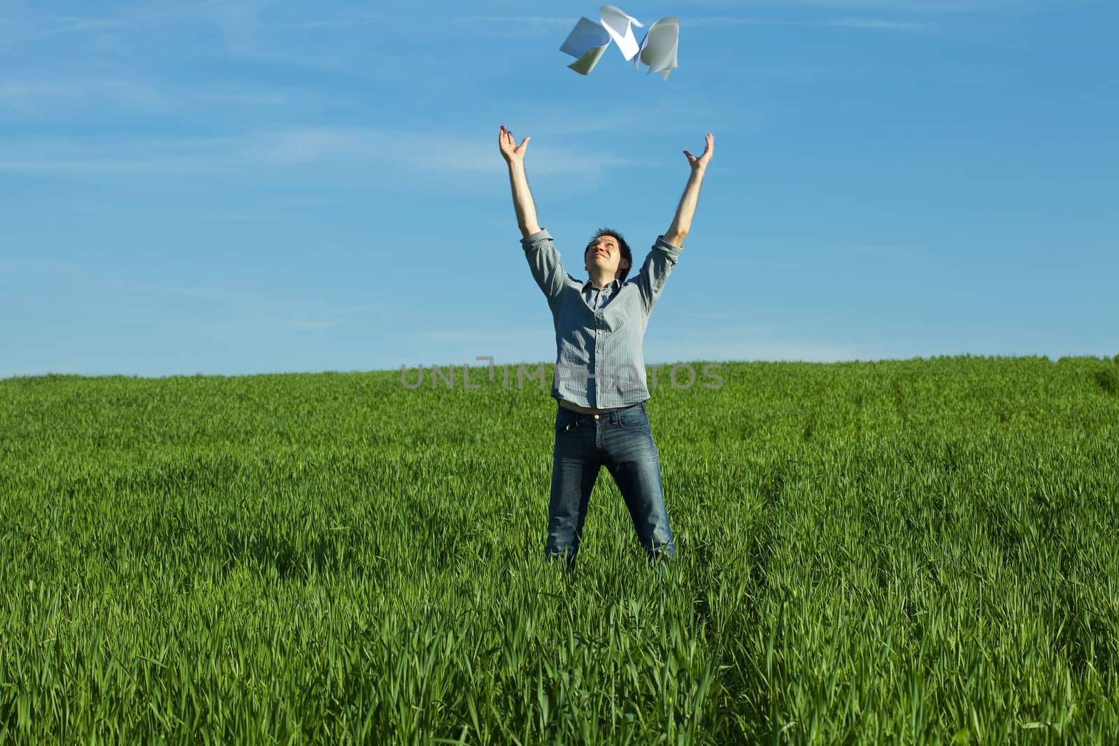 young man throwing a paper in the green field