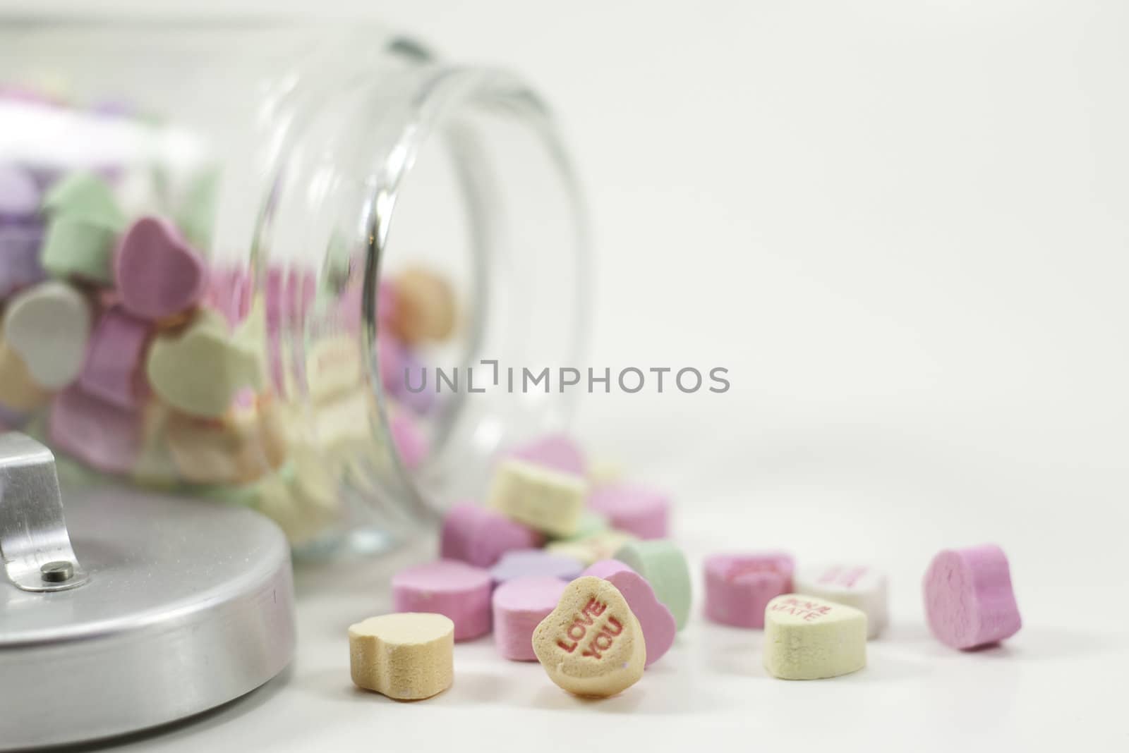 a jar of valentine hearts spilled isolated on white background