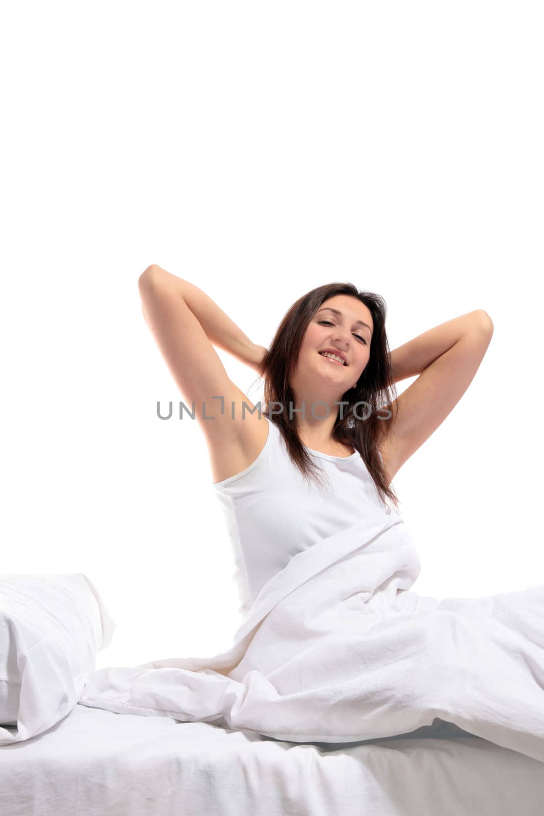 A well rested woman sitting on her bed. All on white background.