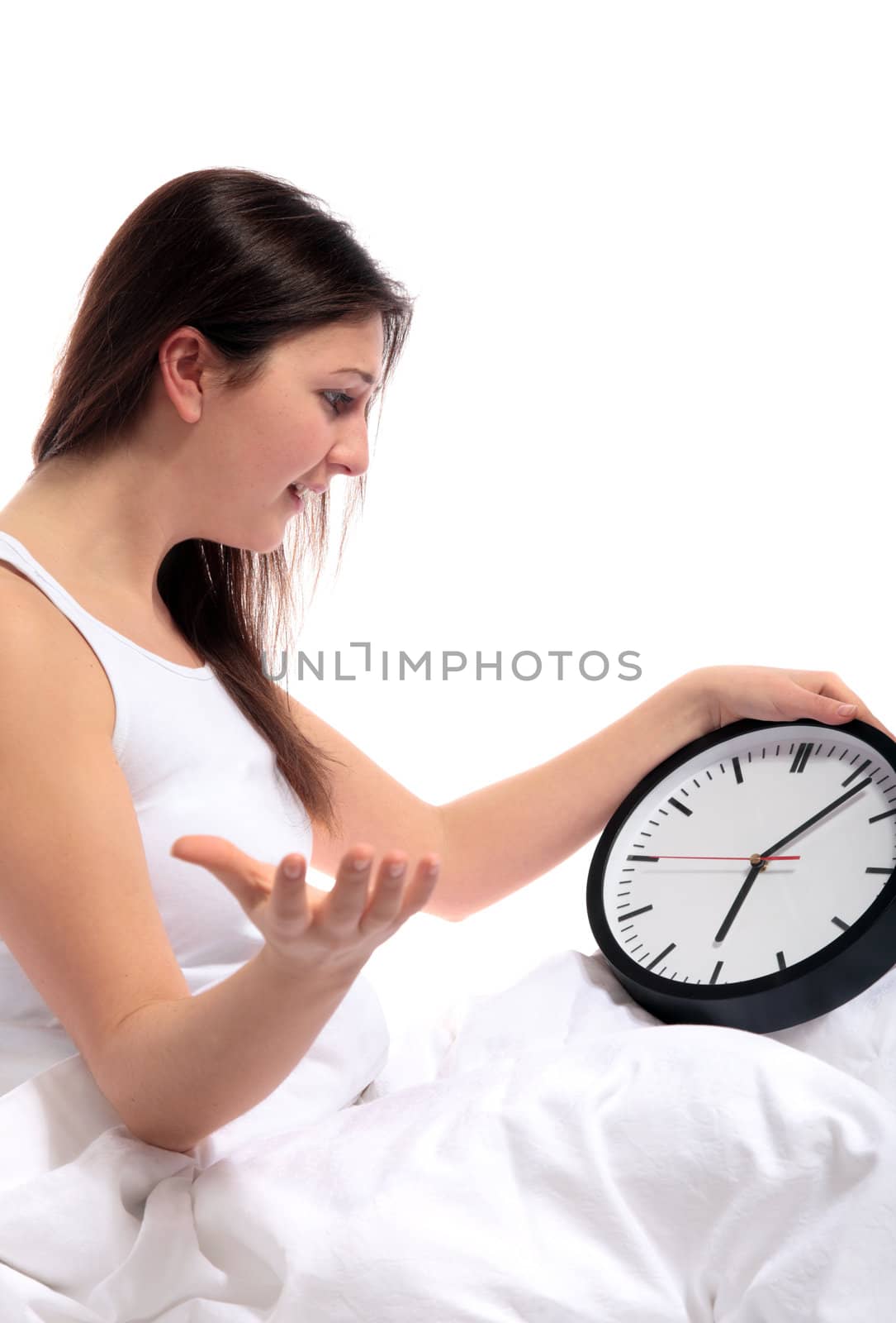 A young woman sitting in her bed whining about her wake-up time. All on white background.