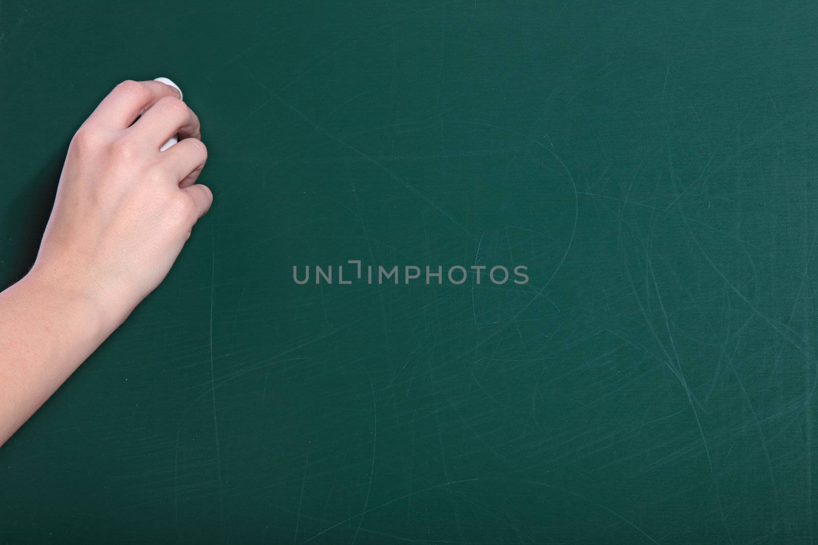 A human hand starts writiing on a blackboard.