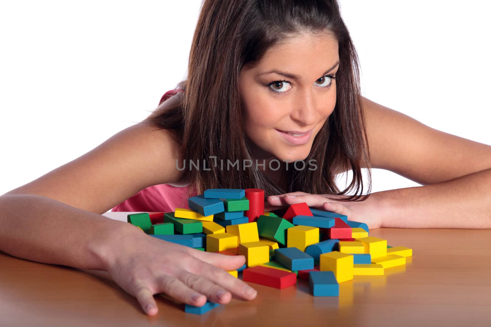 An attractive young woman playing with building bricks. All isolated on white background.