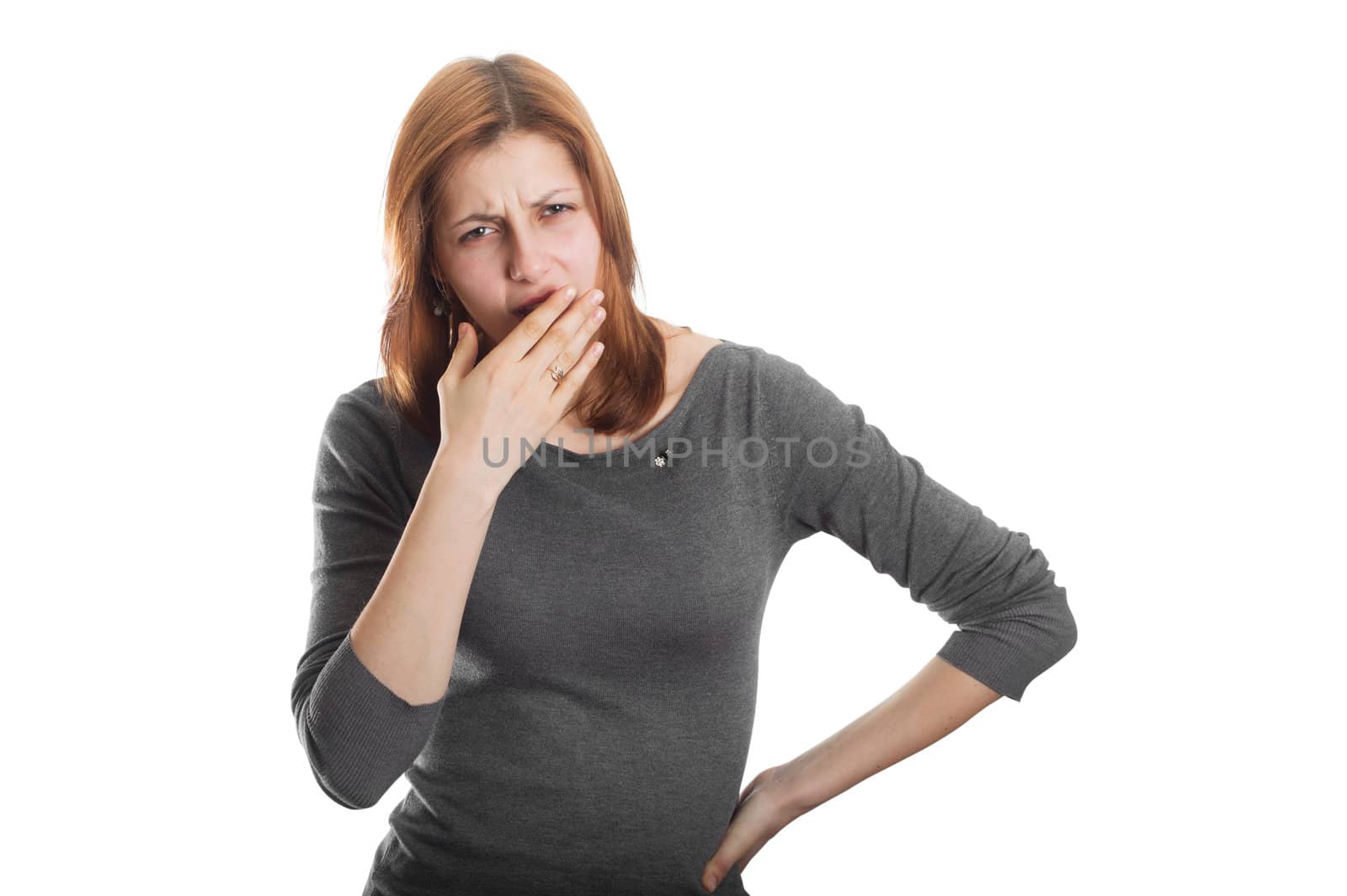 pretty girl yawning behind his hand on a white background isolated
