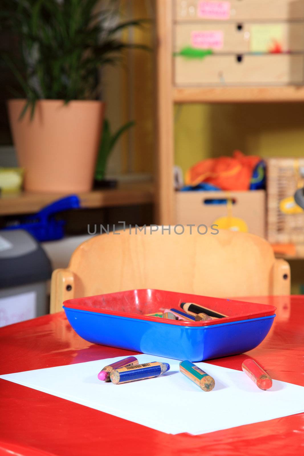 Desk in kindergarten with paper and colored pencils.