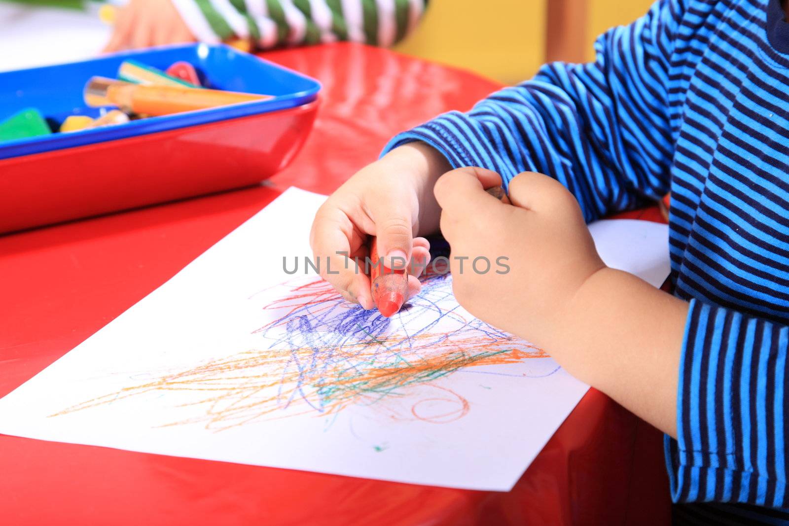 Cute caucasian toddler drawing a picture in kindergarten.