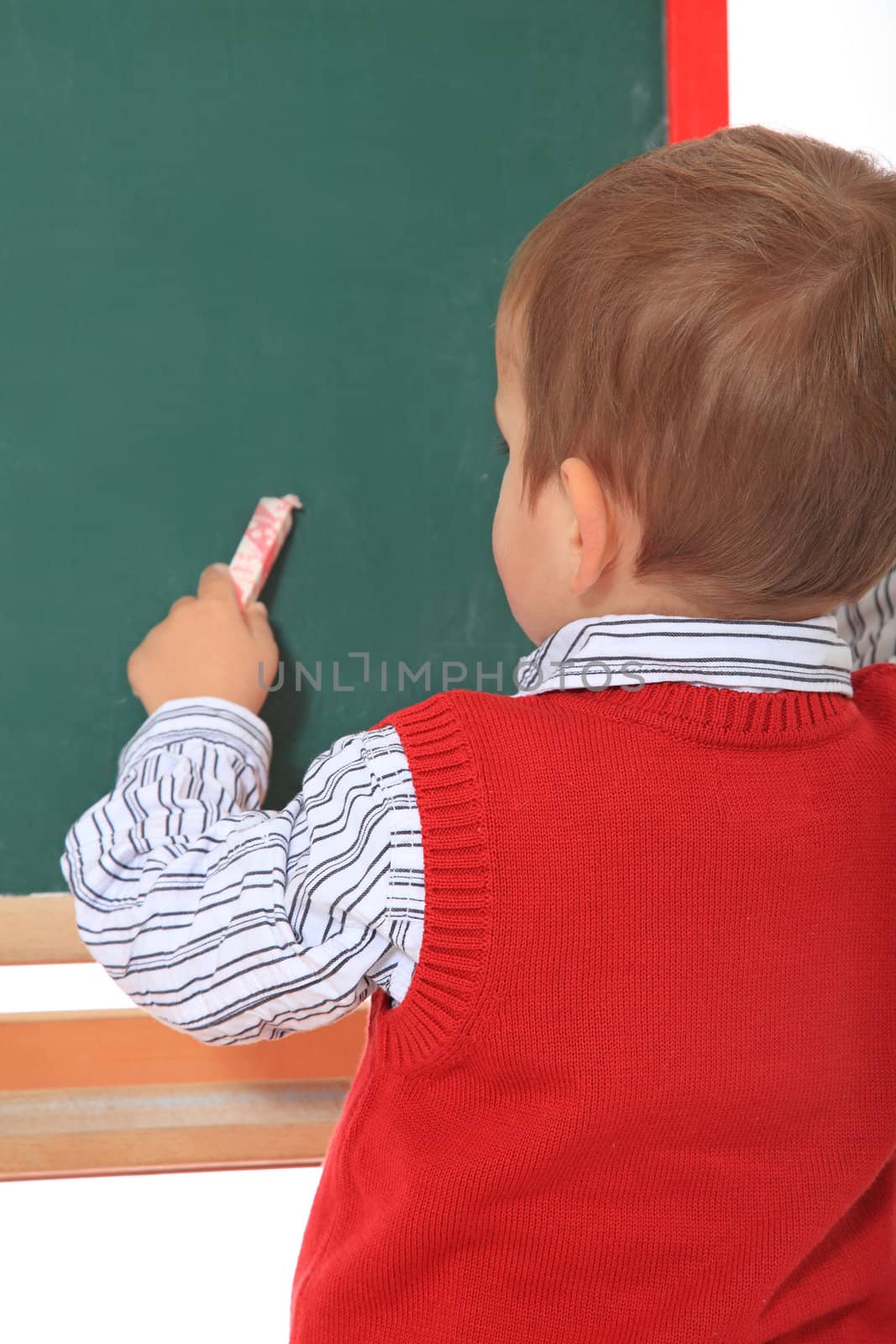 Cute caucasian toddler doodling on chalkboard. All isolated on white background.
