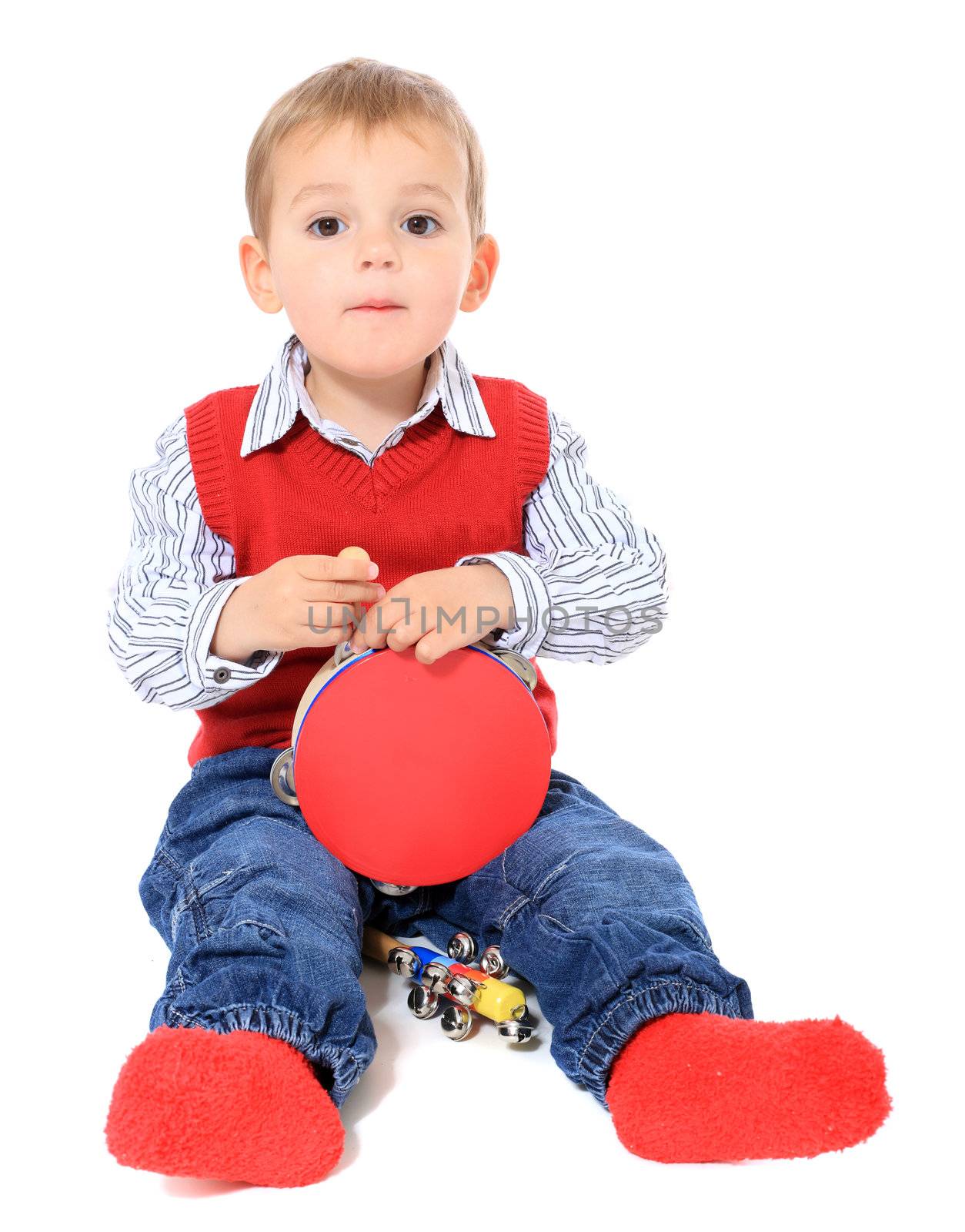 Cute caucasian toddler playing with music instruments. All isolated on white background.