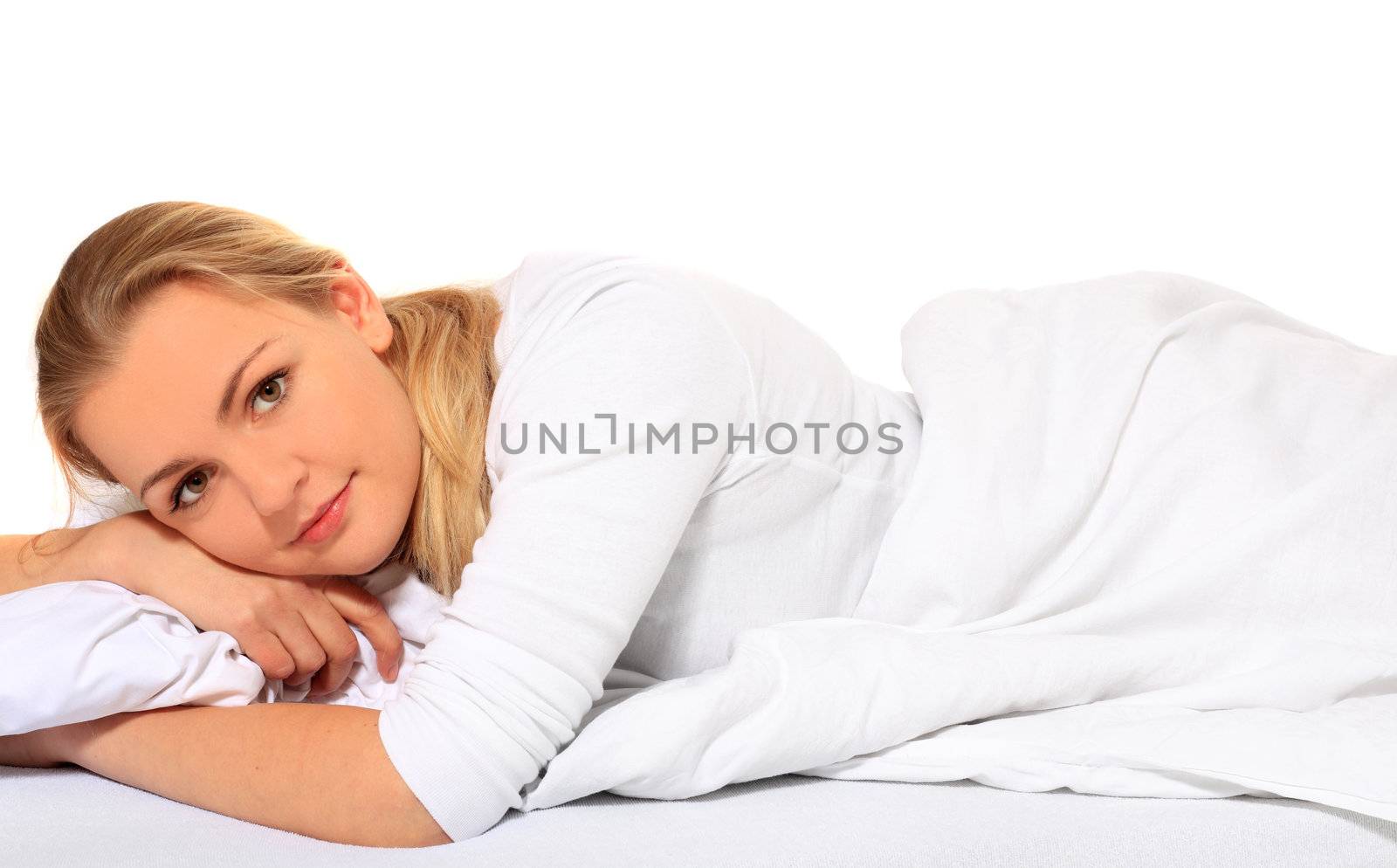 Attractive blond woman lying in bed. All on white background.
