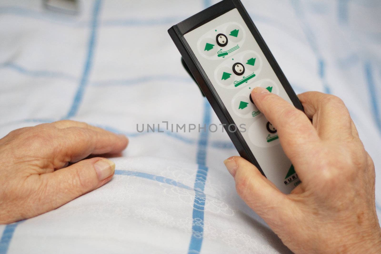 Hands of a care-dependent person holding remote control of an adjustable bed.