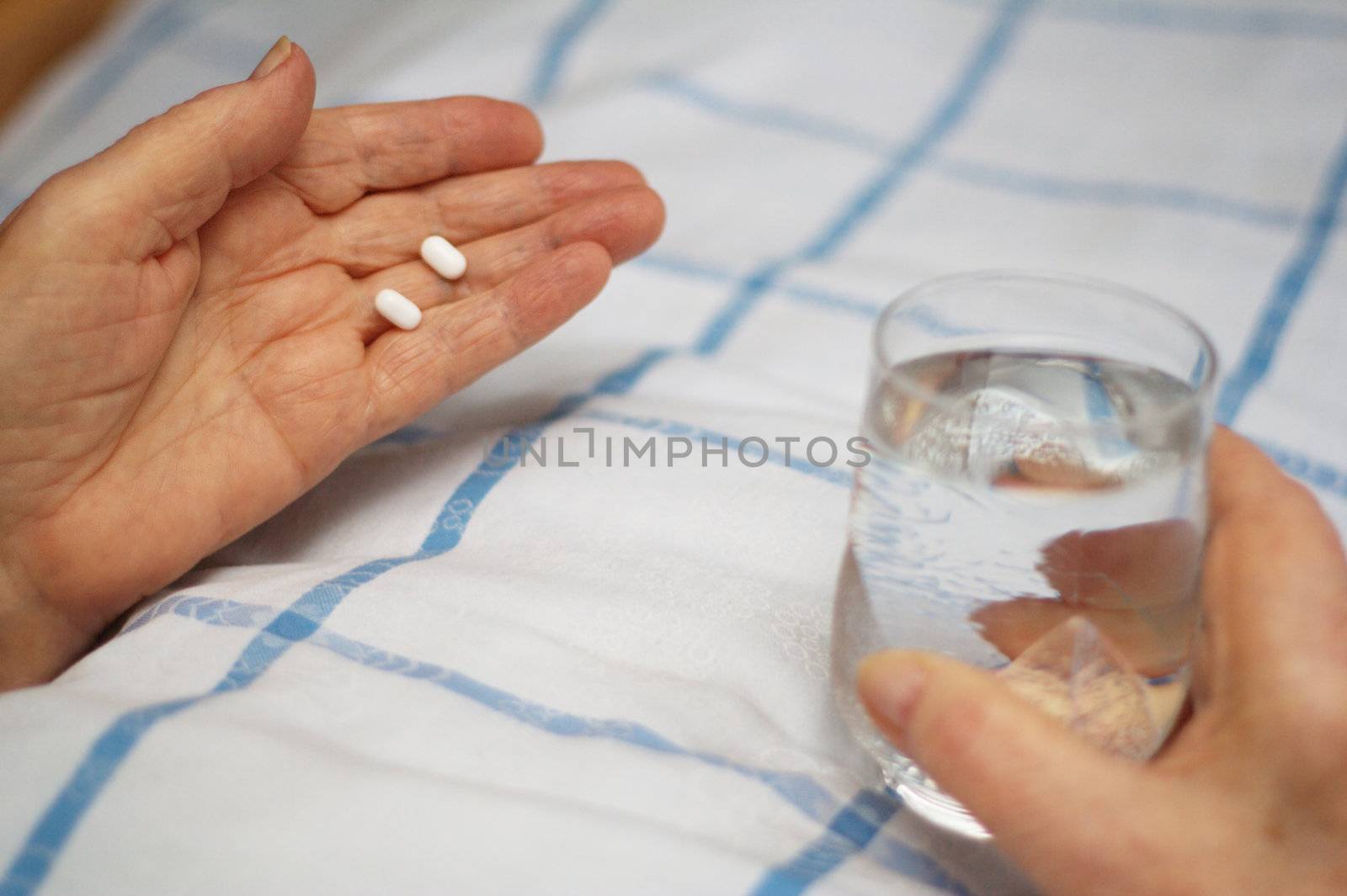 Care-dependent person taking her medicine in bed.