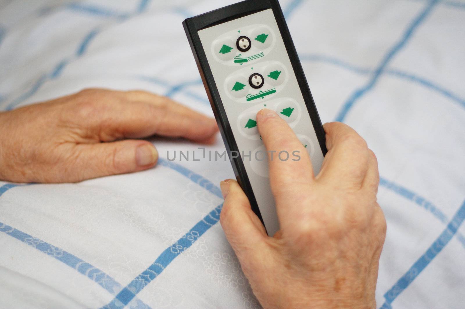 Hands of a care-dependent person holding remote control of an adjustable bed.