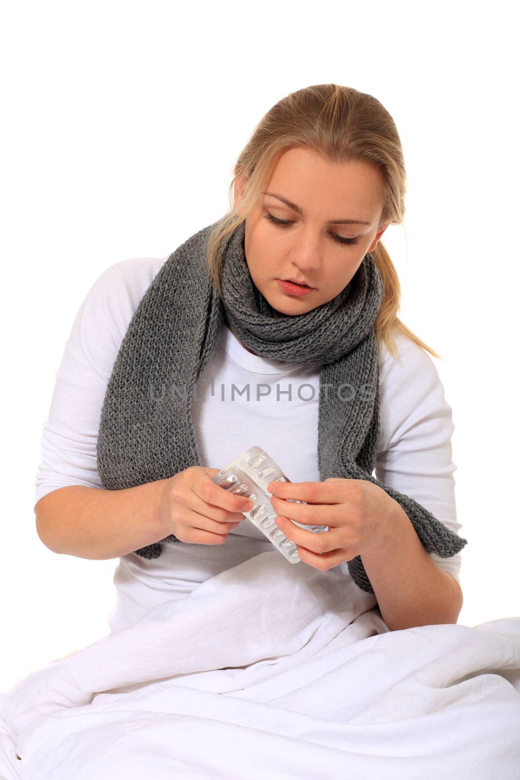 Blond woman sitting in bed taking pharmaceuticals. All on white background.