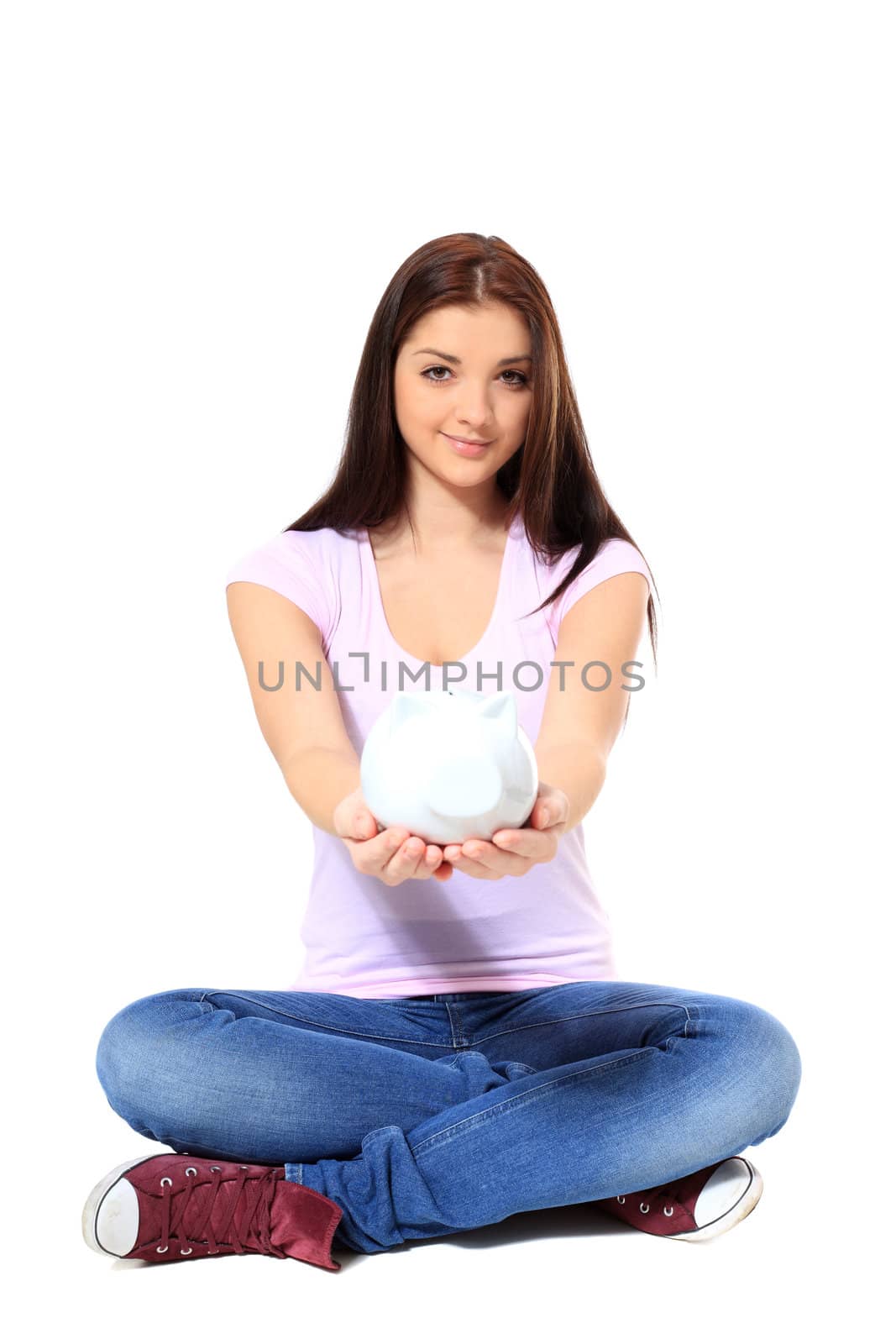 Attractive teenage girl holding piggy bank. All on white background.