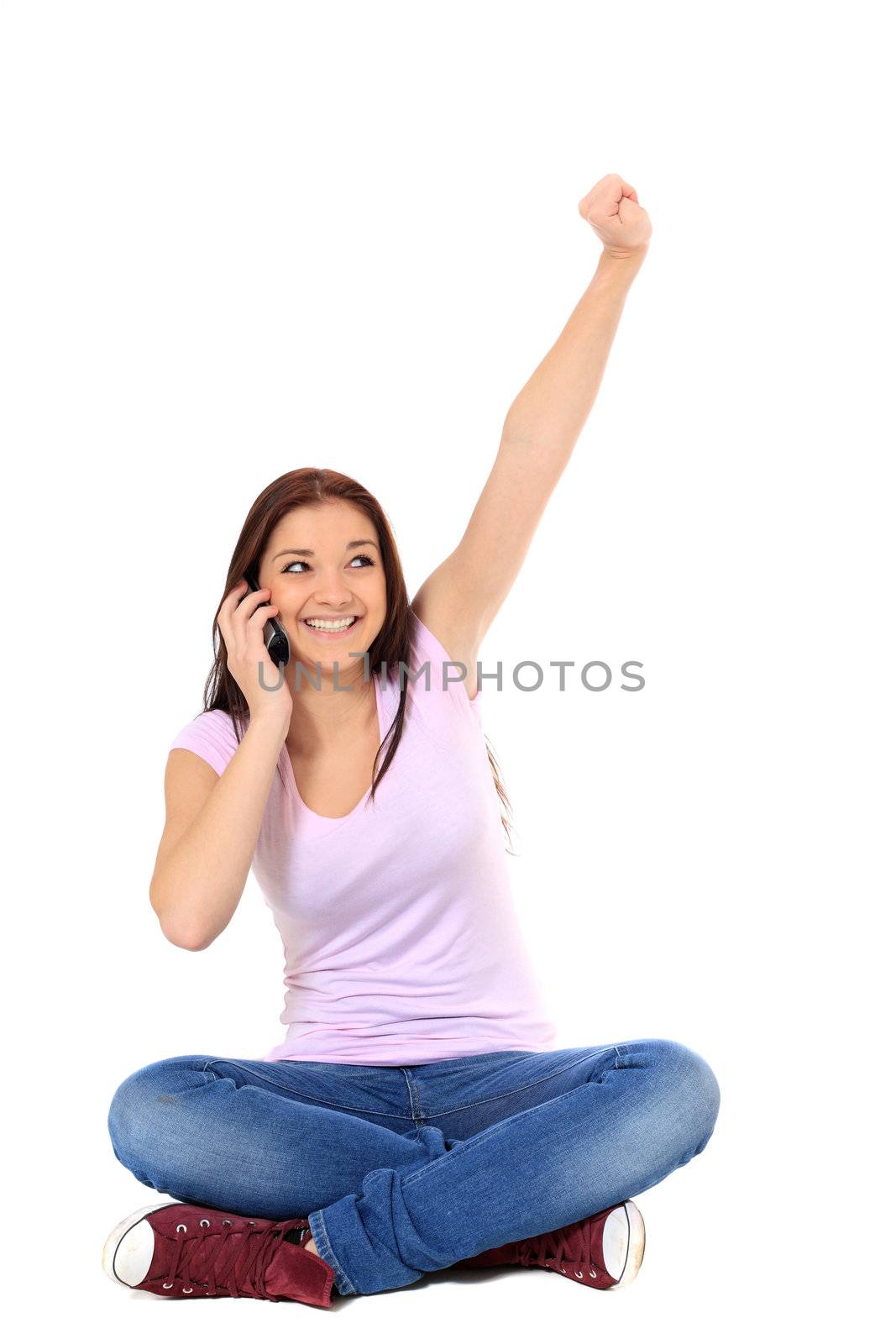 Attractive teenage girl cheering during phone call. All on white background.