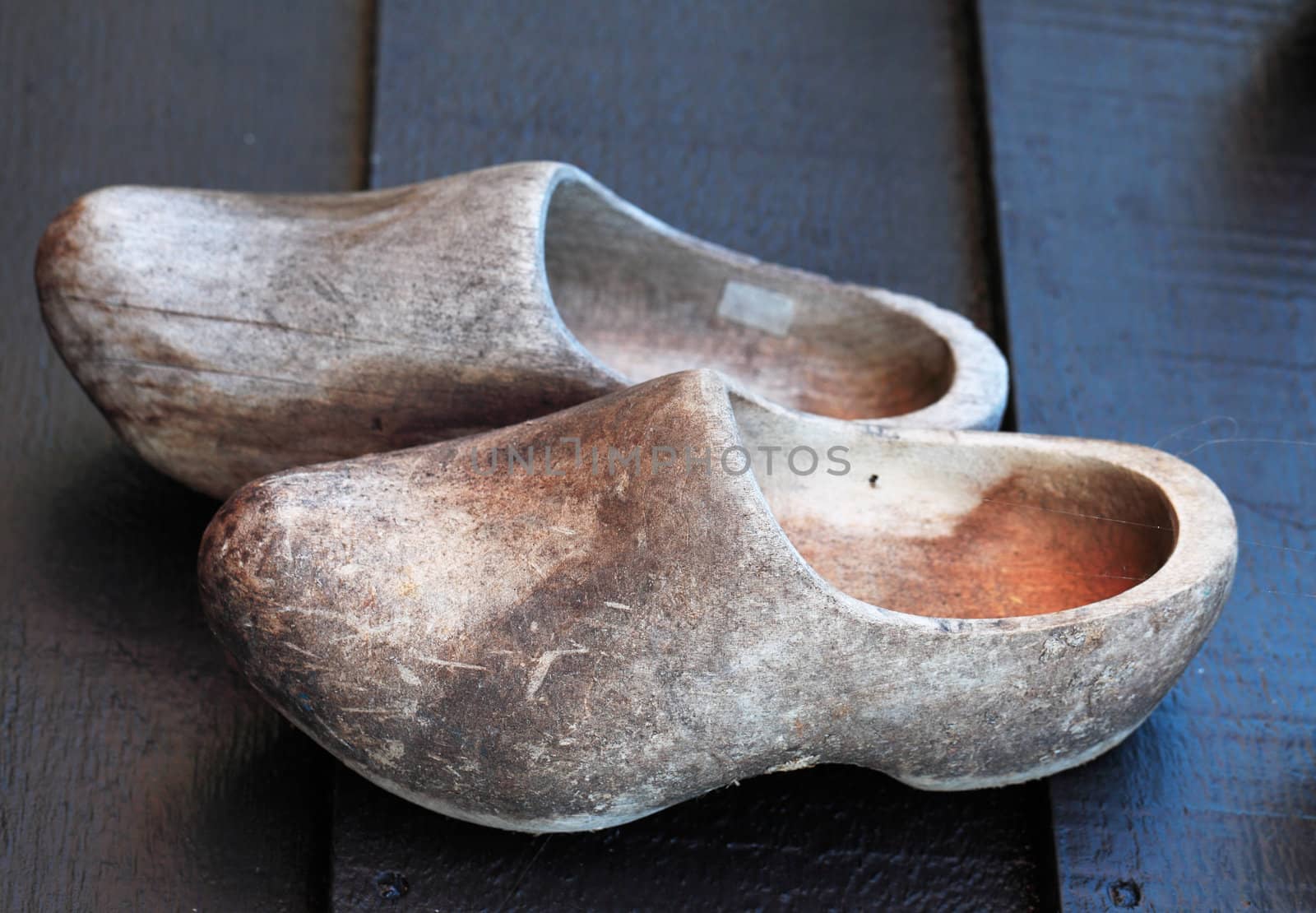 Old used traditional dutch wooden clogs on a wooden surface.