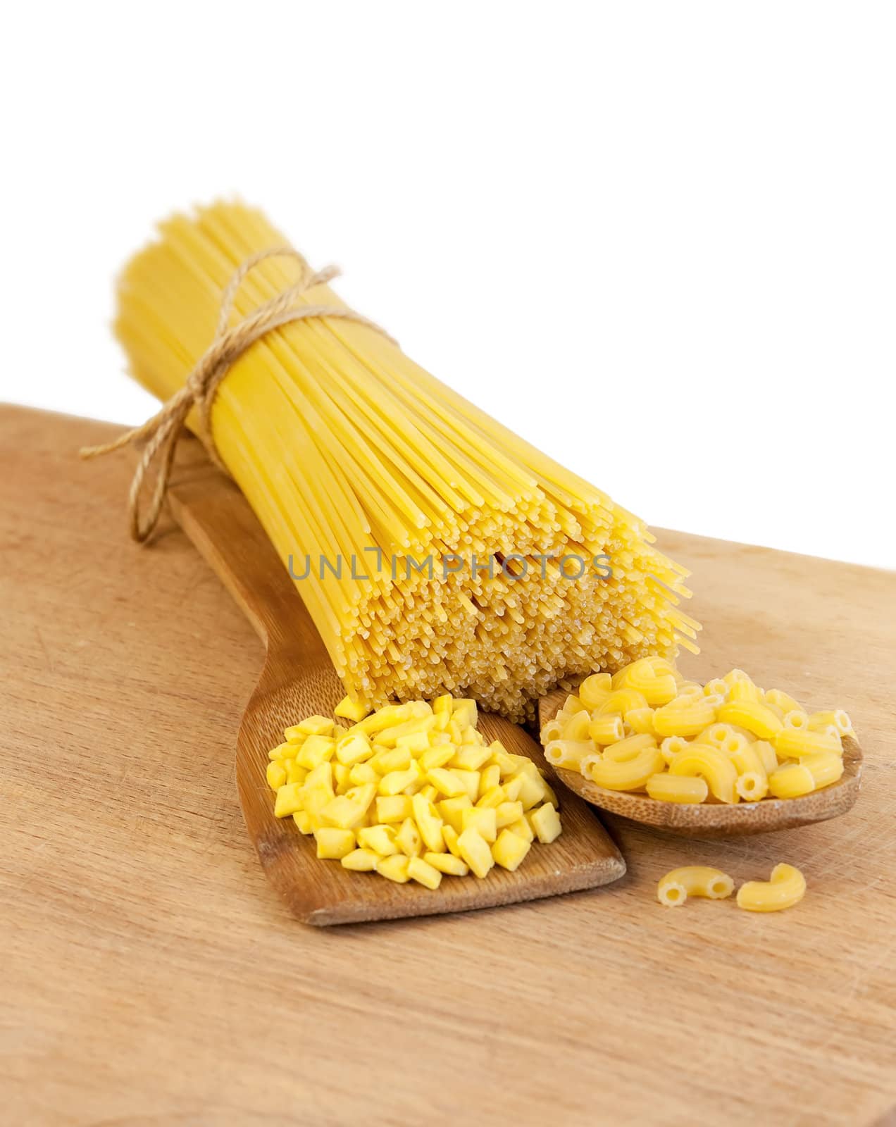 pasta and wooden spoon on a wooden board on a white background