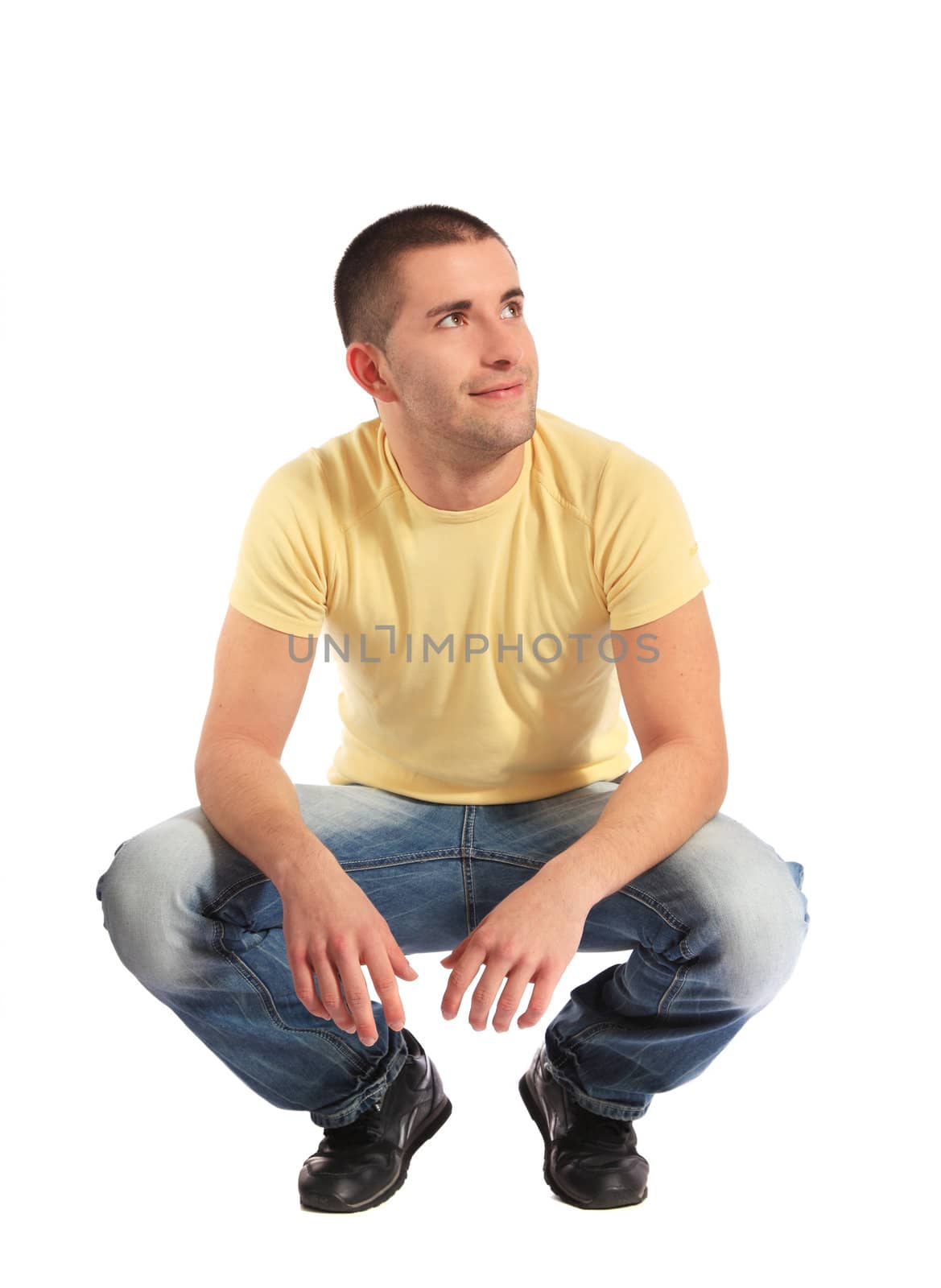 Attractive young man in squatting position. All on white background