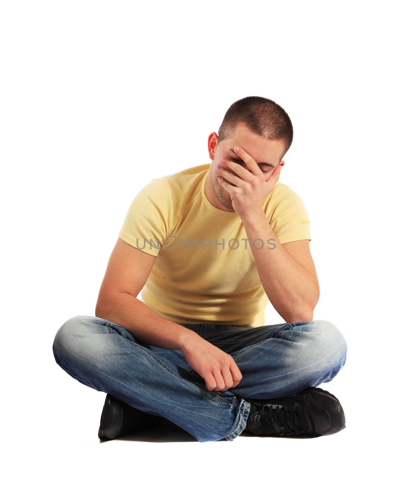 Attractive young man sitting in desperate mood. All on white background.