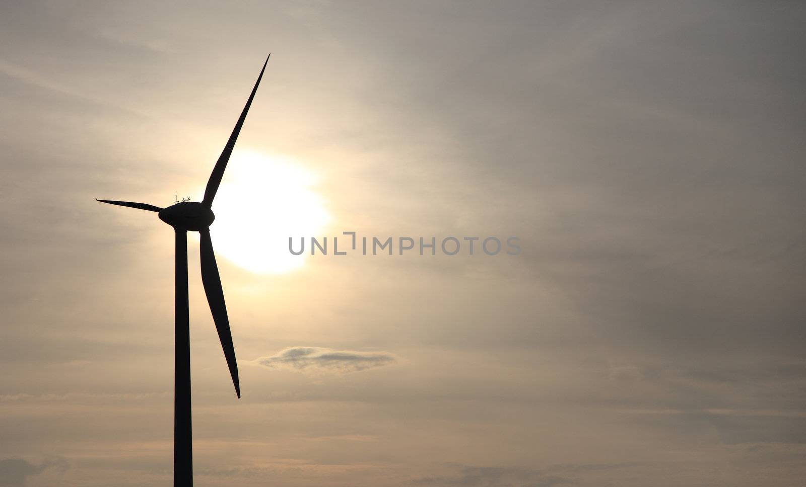 Silhouette of a wind power plant in front of sunset.