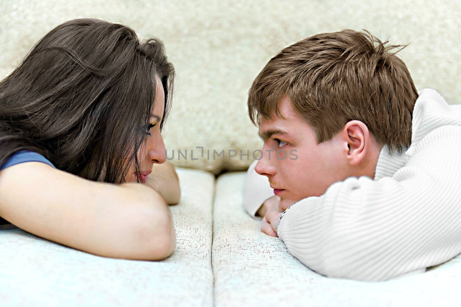 young boy and girl look at each other while lying on bed