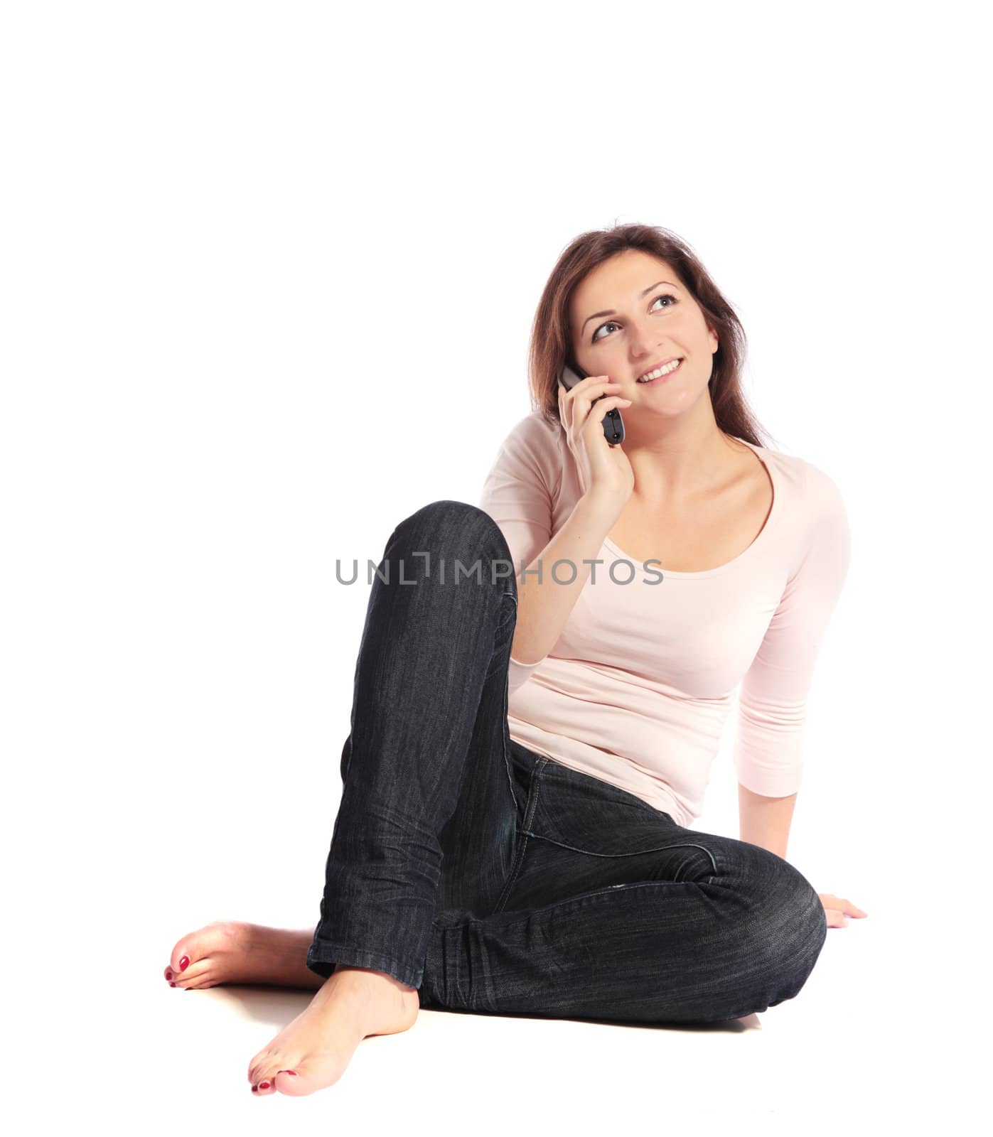 Attractive young woman sitting on the floor, having a phone call. All on white background.