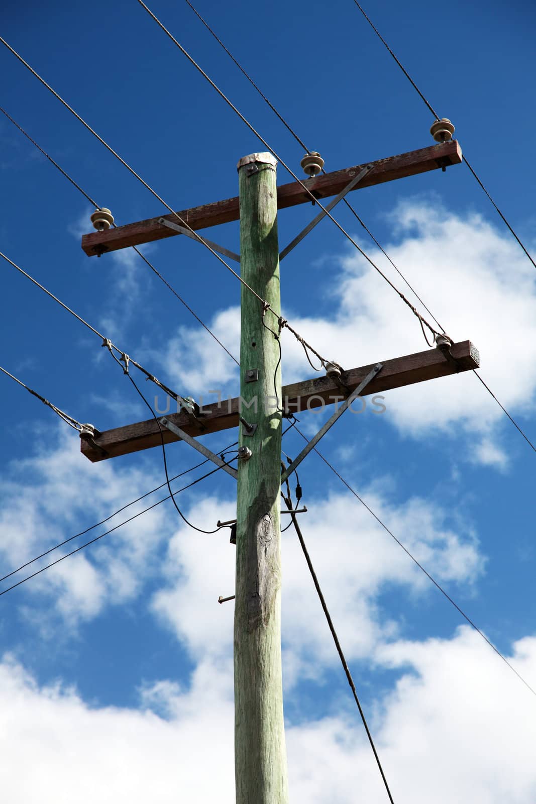 Power pole in front of light cloudy sky.