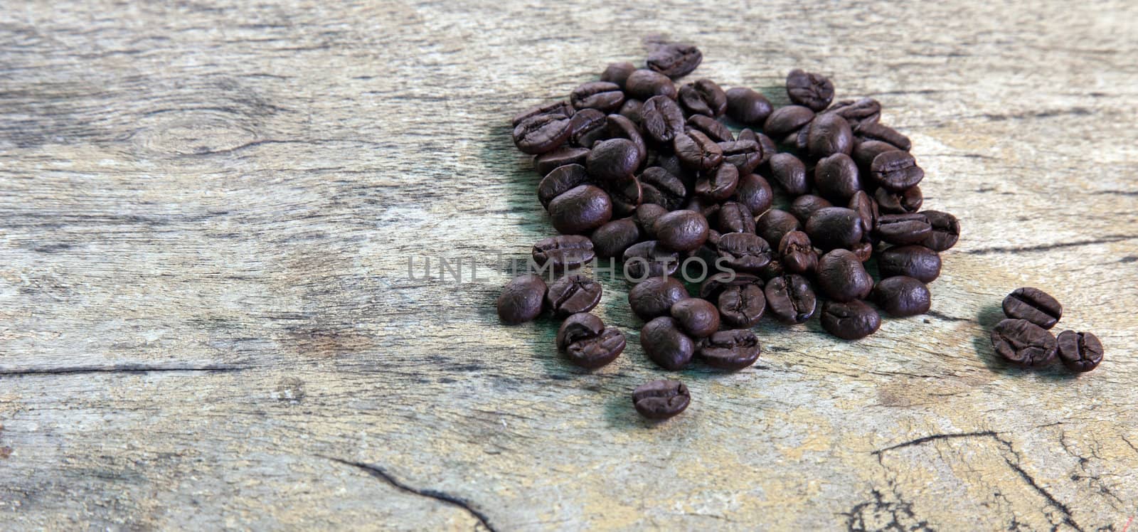 Coffee beans in dark roast level on rustic wooden board.