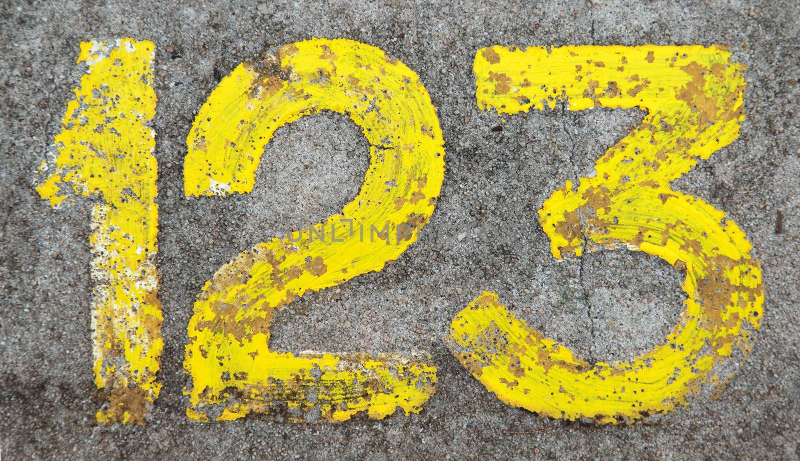 123 painted in yellow on grey concrete ground.